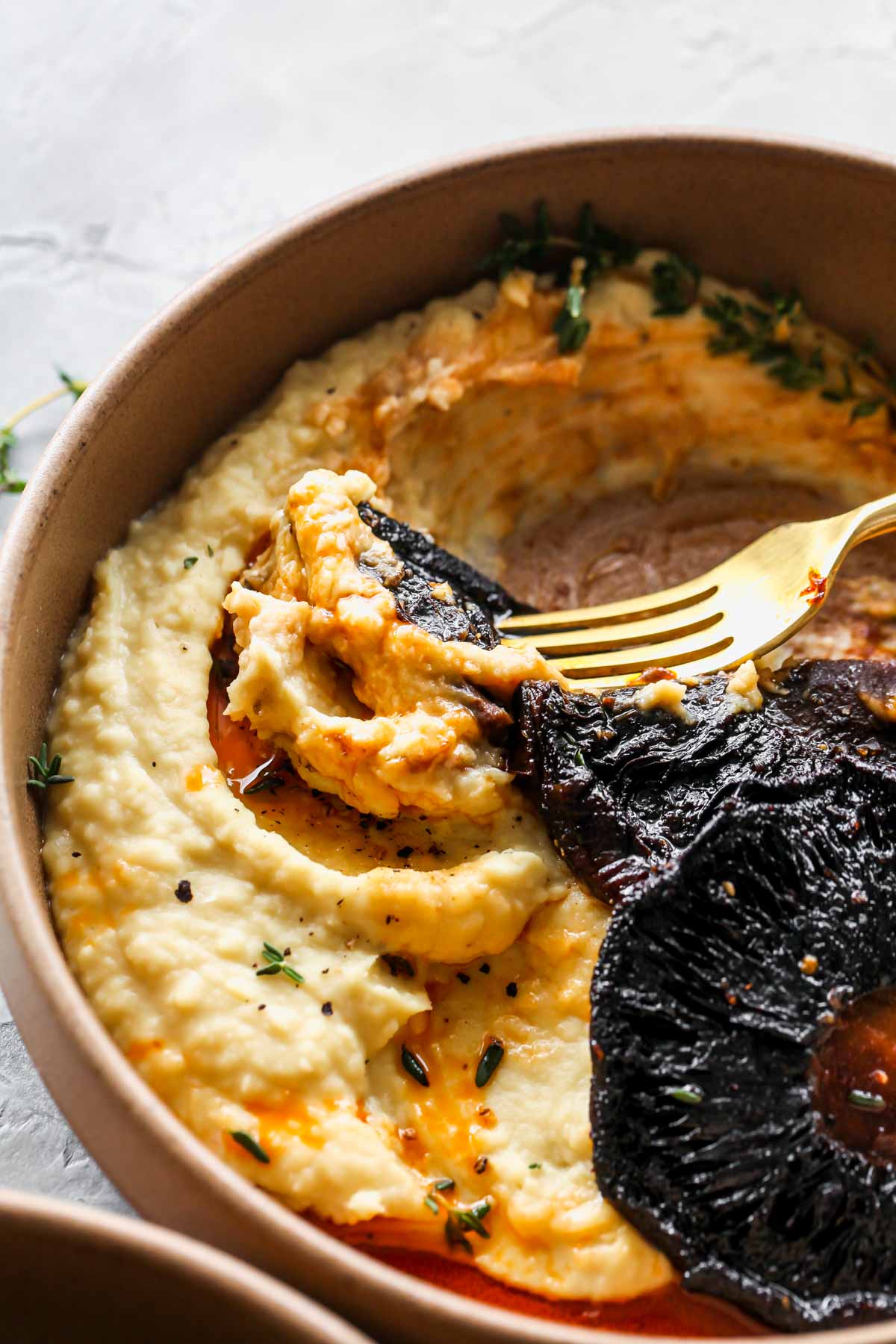 Piece of roasted mushroom being dipped in butter bean mash