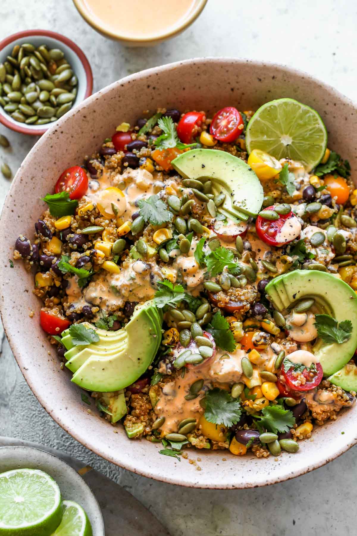 Southwest quinoa salad styled in a pink bowl topped with avocado slices
