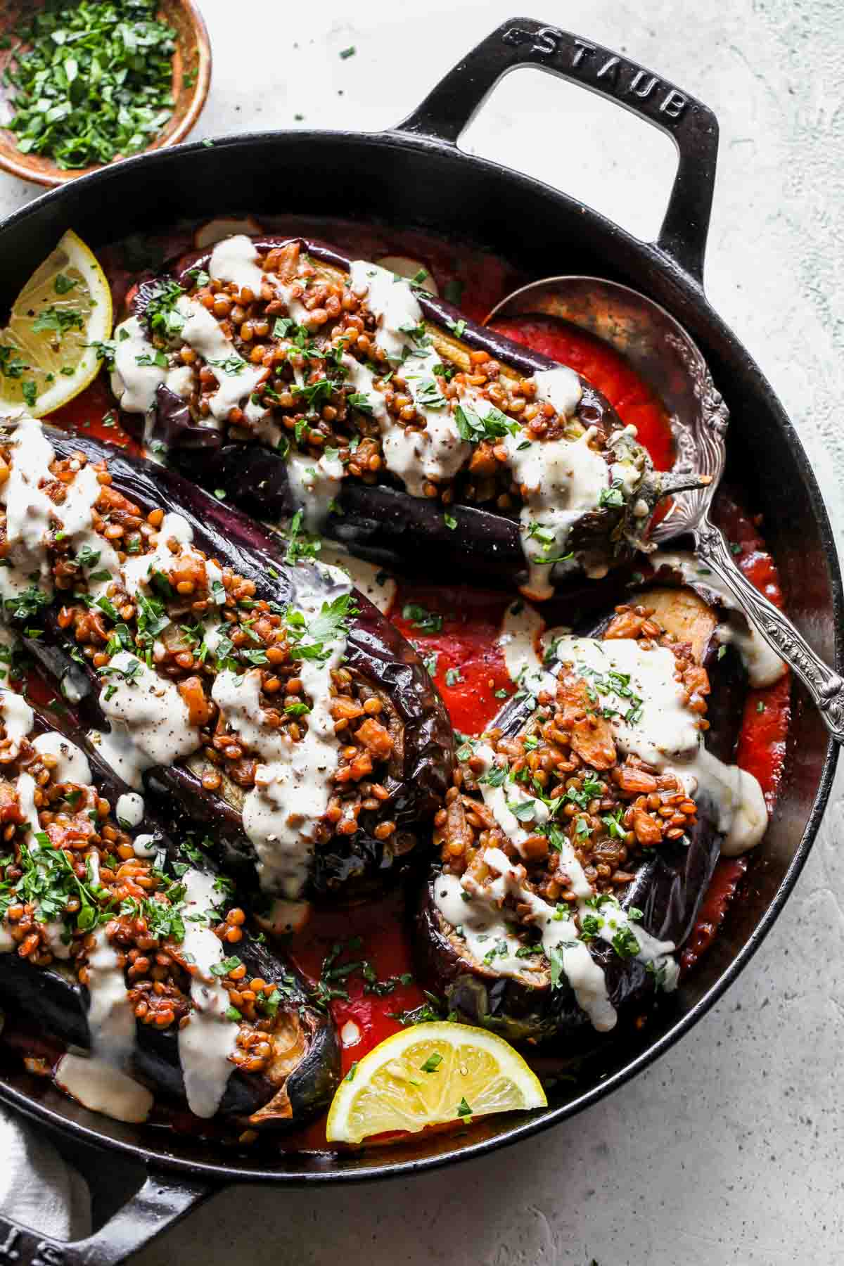 Lentil stuffed eggplants in a pan over tomato sauce