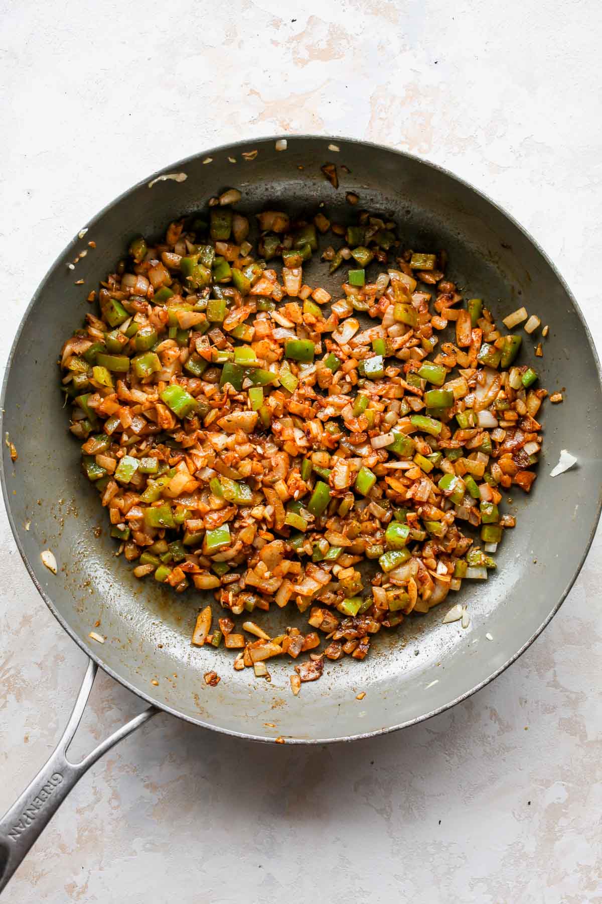 Peppers and onions being sautéed in a skillet