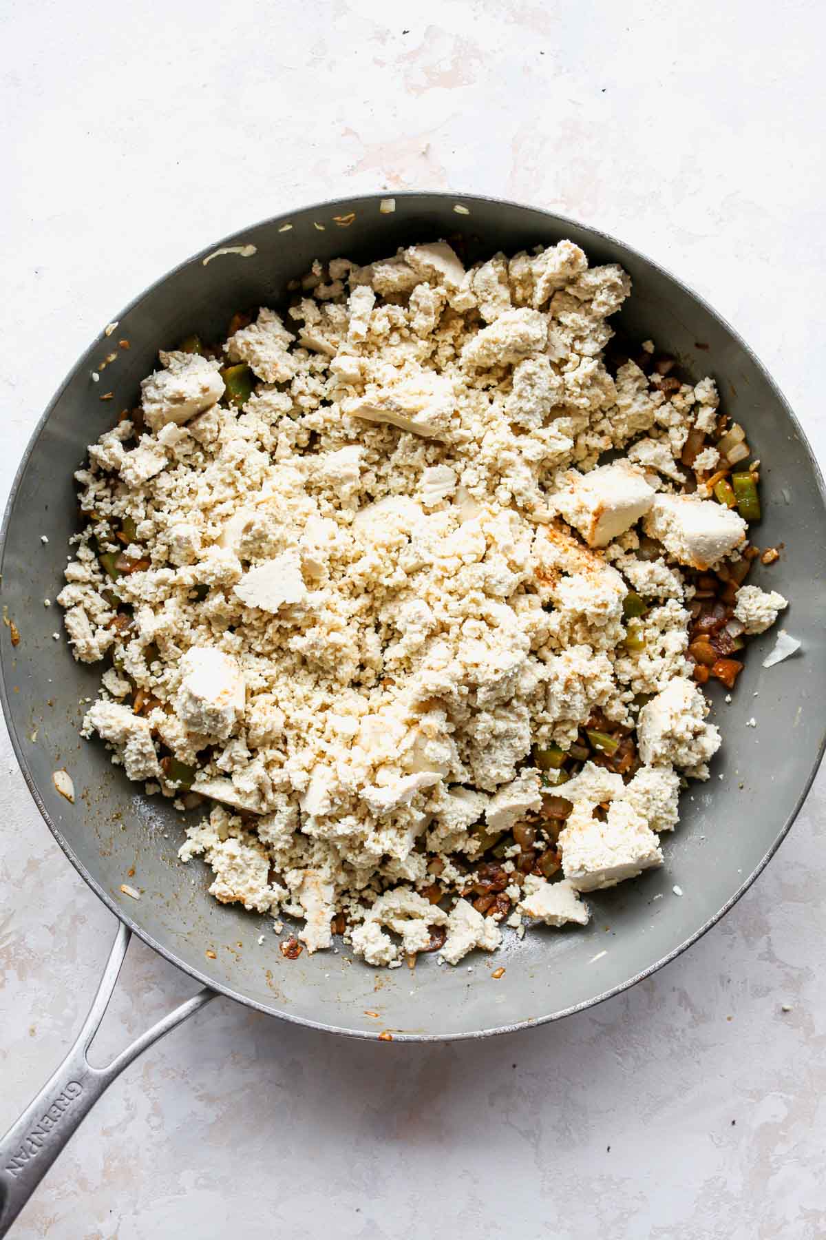 Crumbled tofu being sauteed in a large skillet