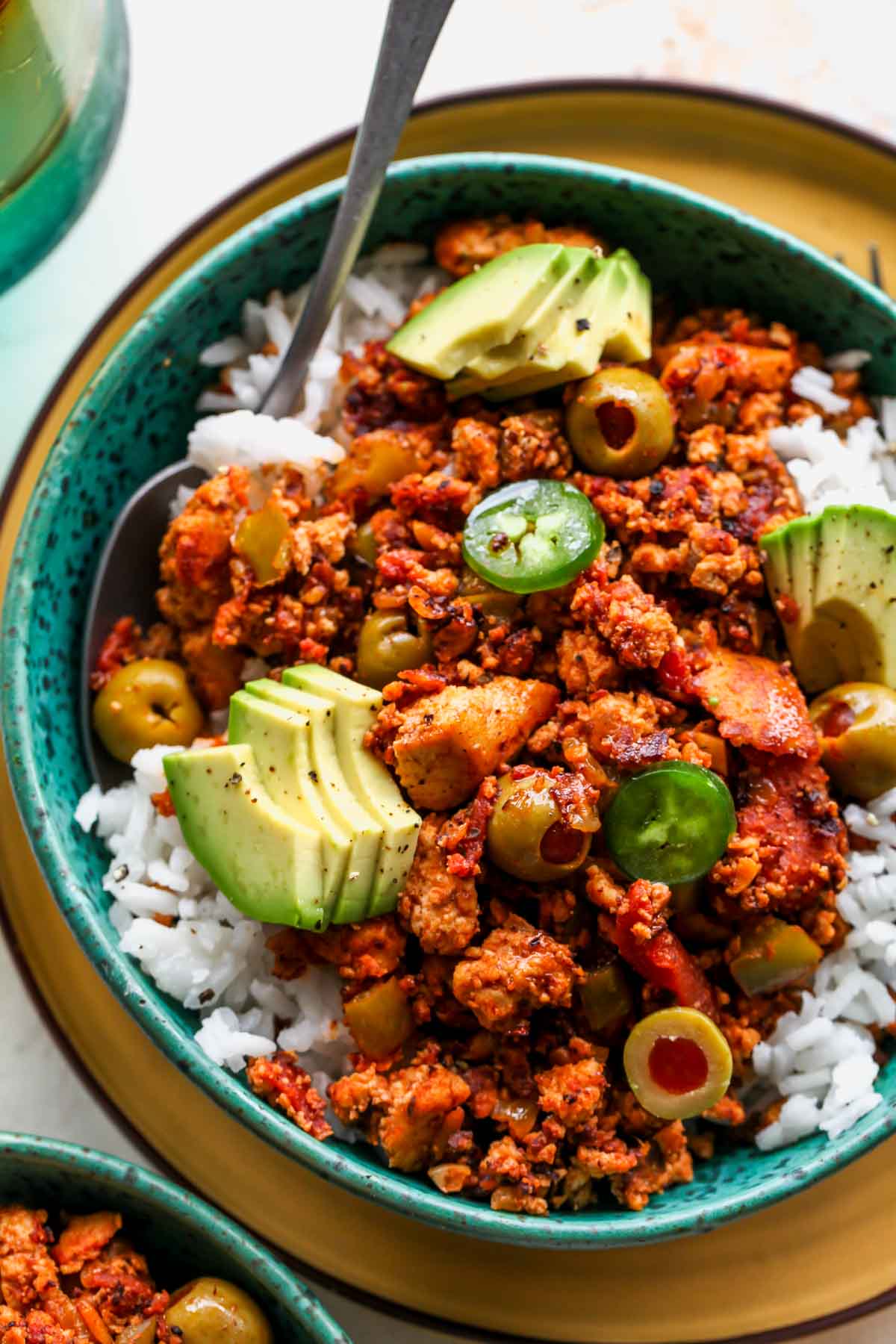 A spoon taking out a bite of picadillo from a blue bowl