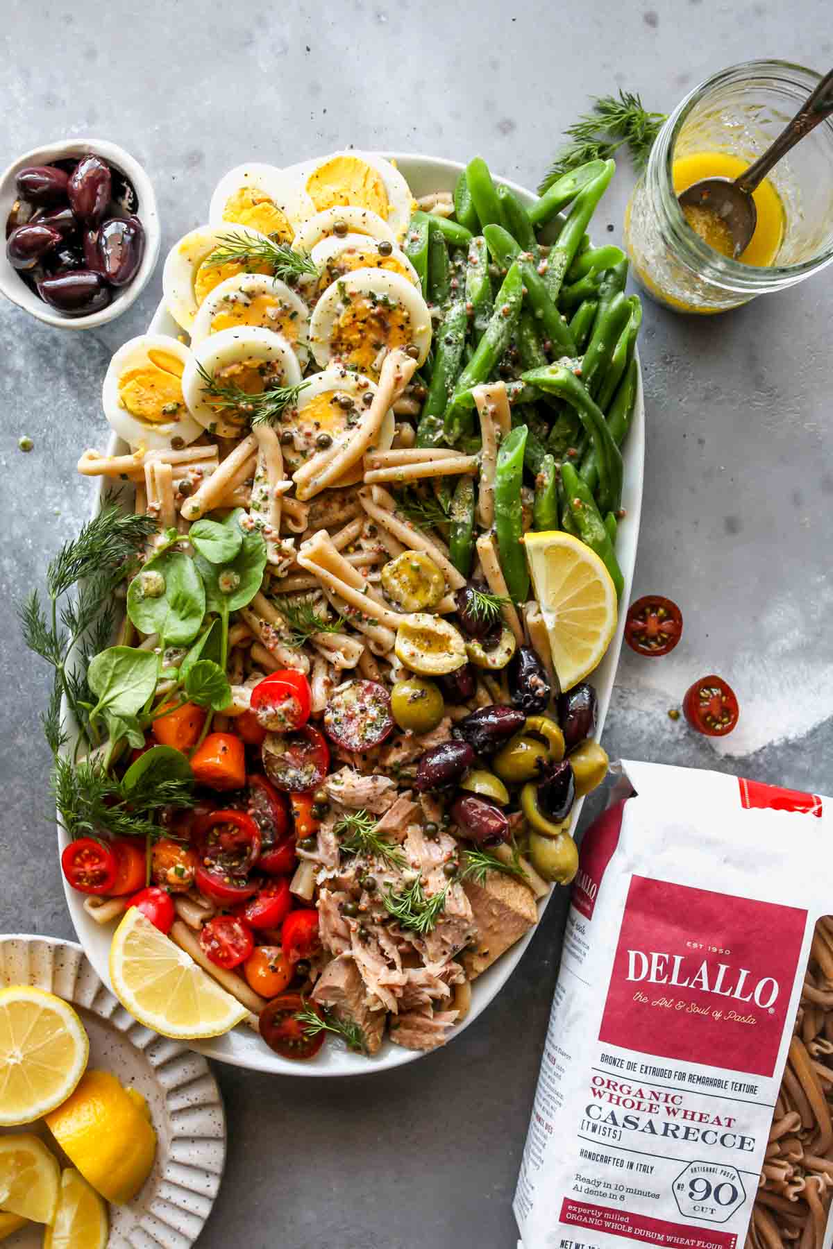 DeLallo pasta bag next to a platter of Niçoise Pasta Salad