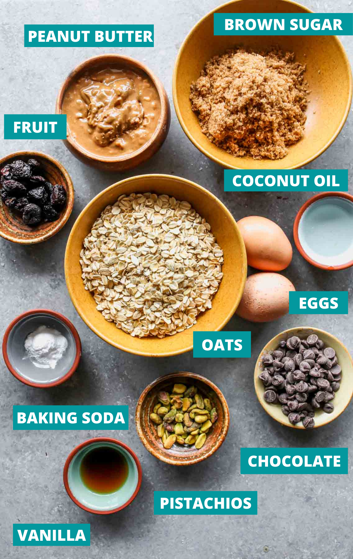 Cookie ingredients in bowls on a grey surface with blue labels