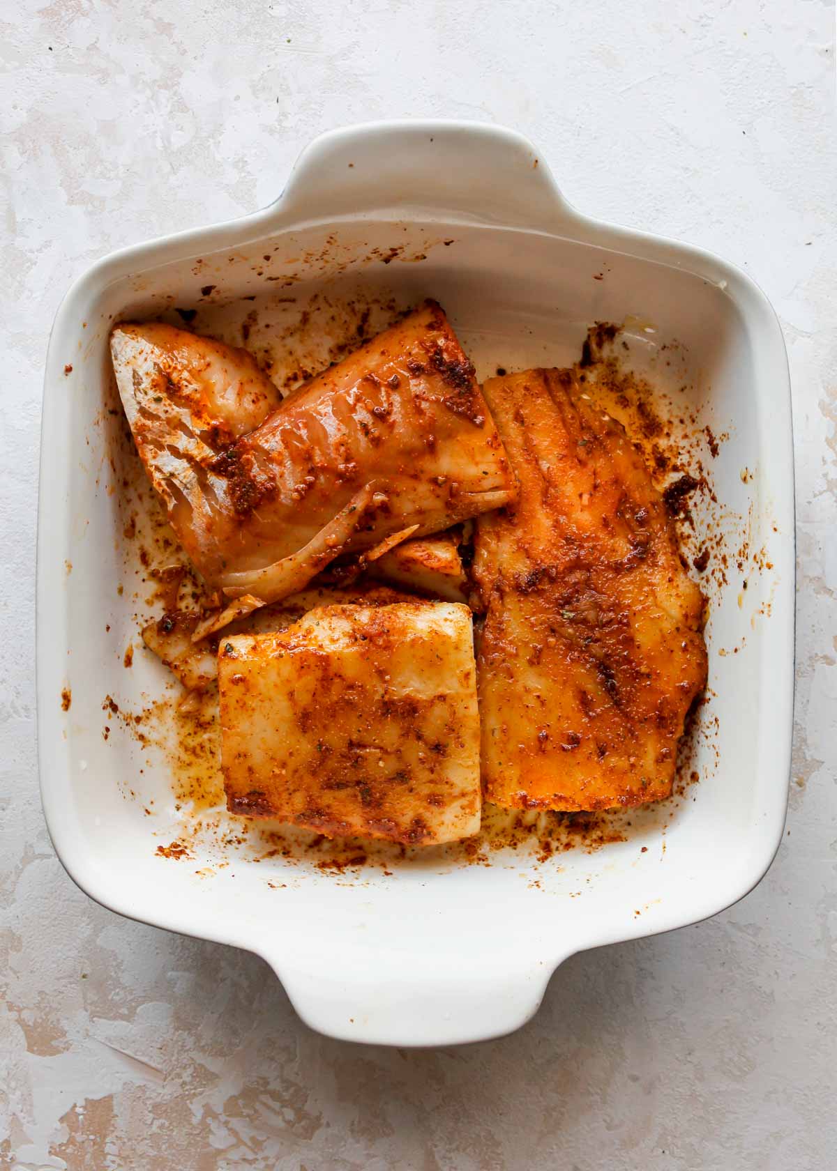 Cod marinating in a spice mixture in a dish