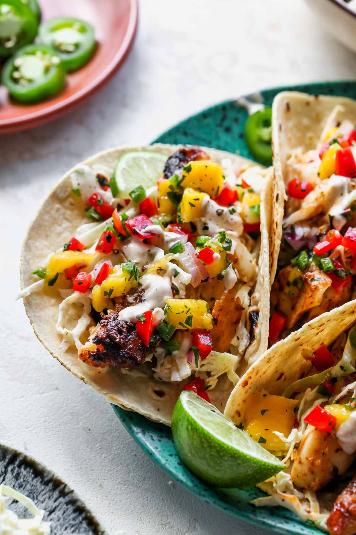Fish tacos with mango salsa and slaw arranged on a teal plate