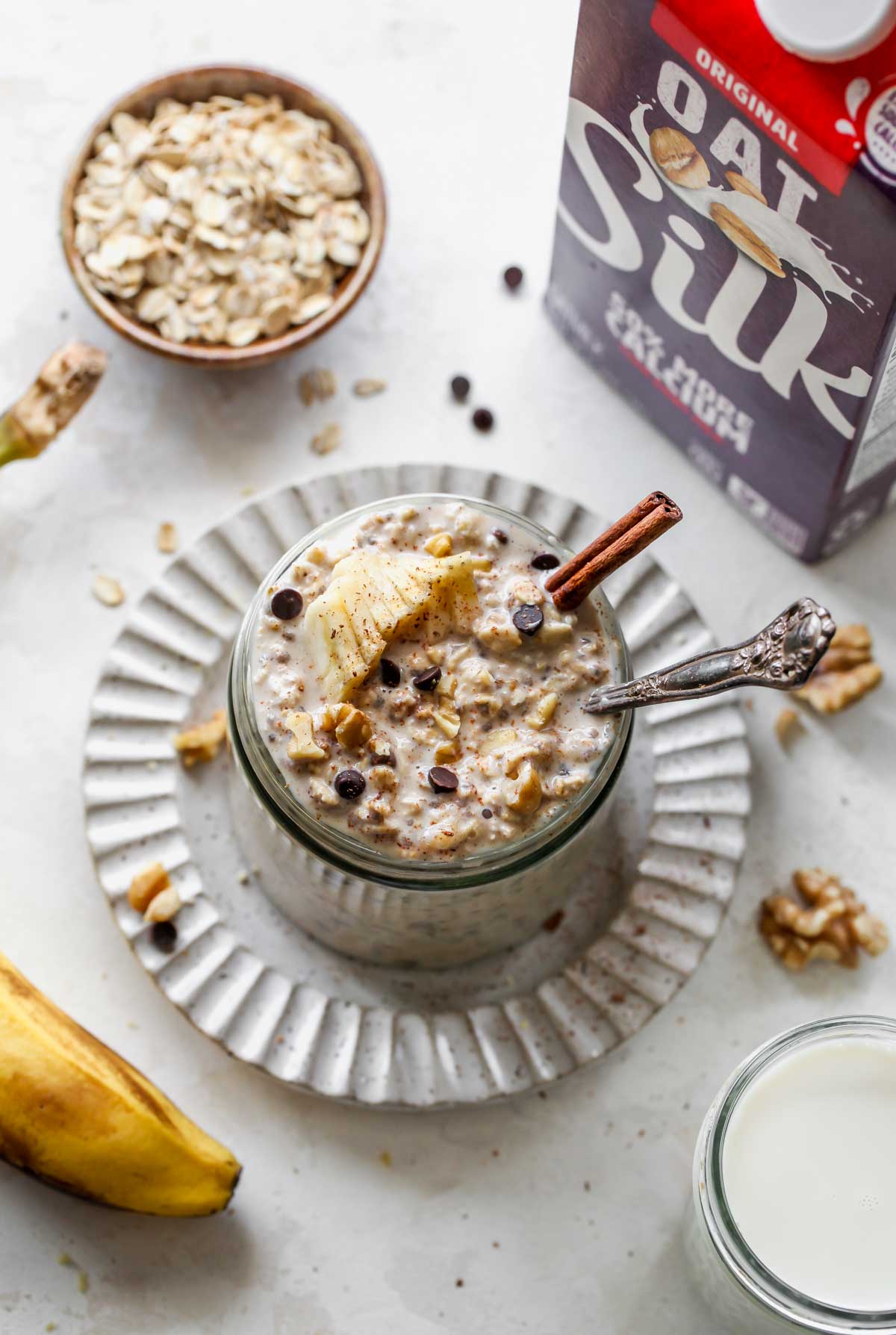 Jar of banana overnight oats next to a carton of oatmilk