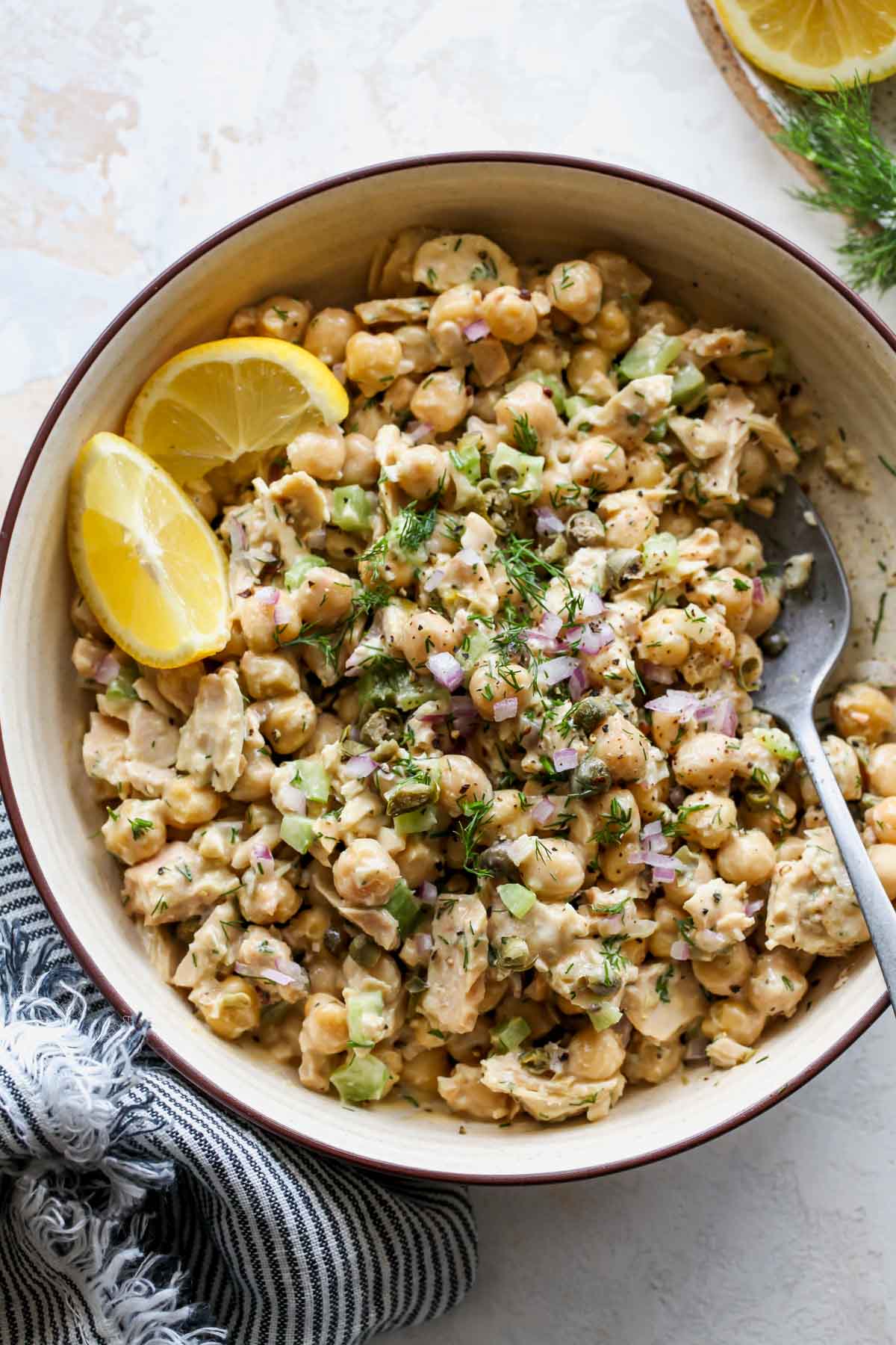 Lemony garbanzo bean salad being mixed with herbs in a bowl