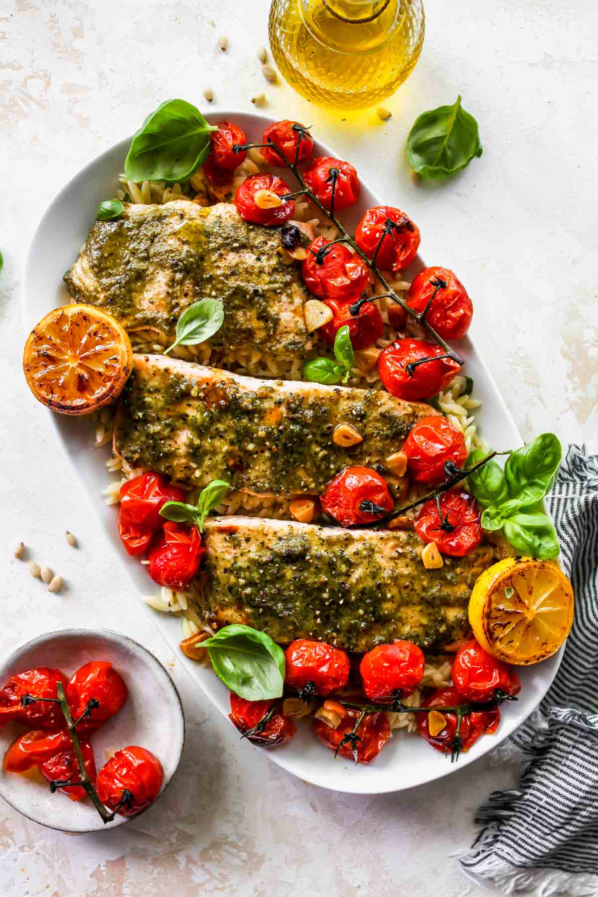 Three salmon fillets on a platter over orzo with roasted tomatoes