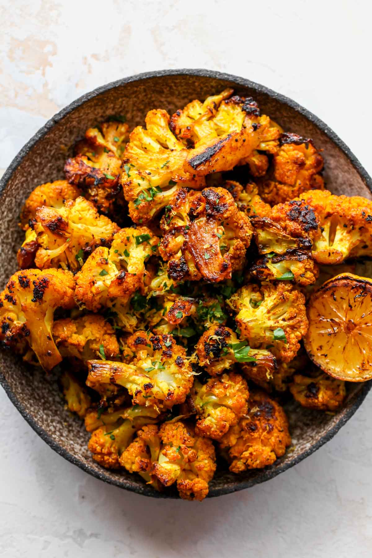 Turmeric roasted cauliflower topped with lemon zest in a bowl