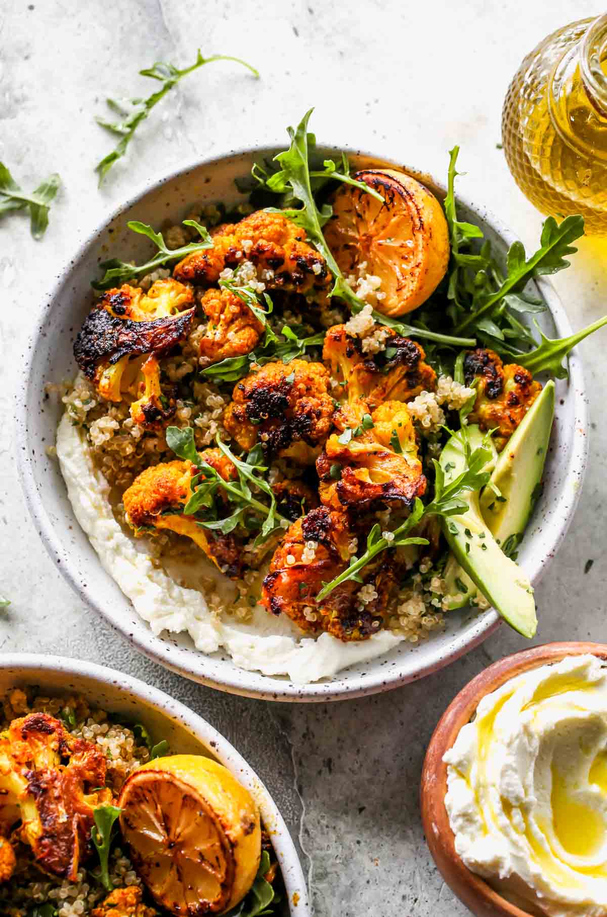 Turmeric roasted cauliflower florets with quinoa and arugula in a while bowl