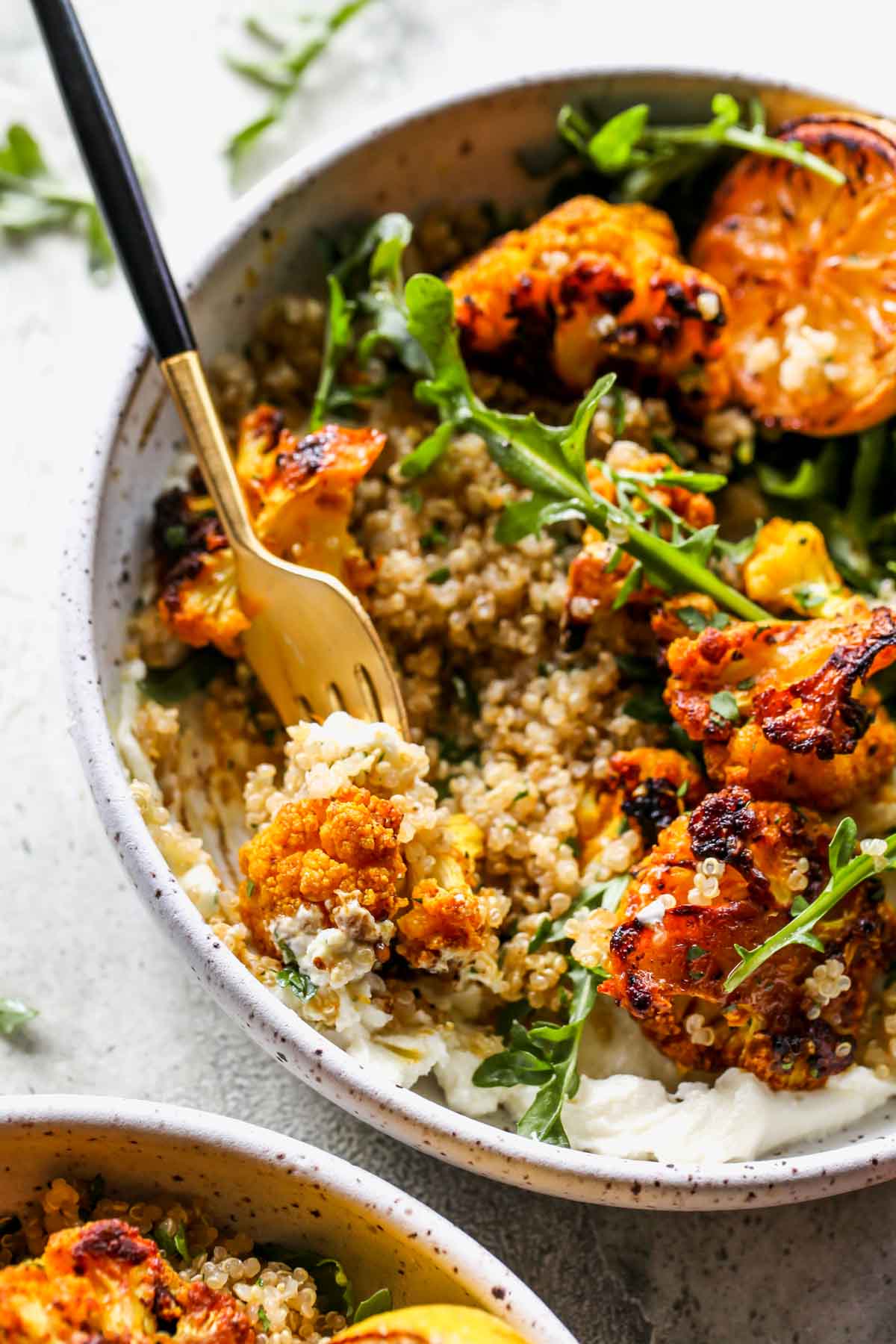 A fork picking up a bite of cauliflower and whipped feta