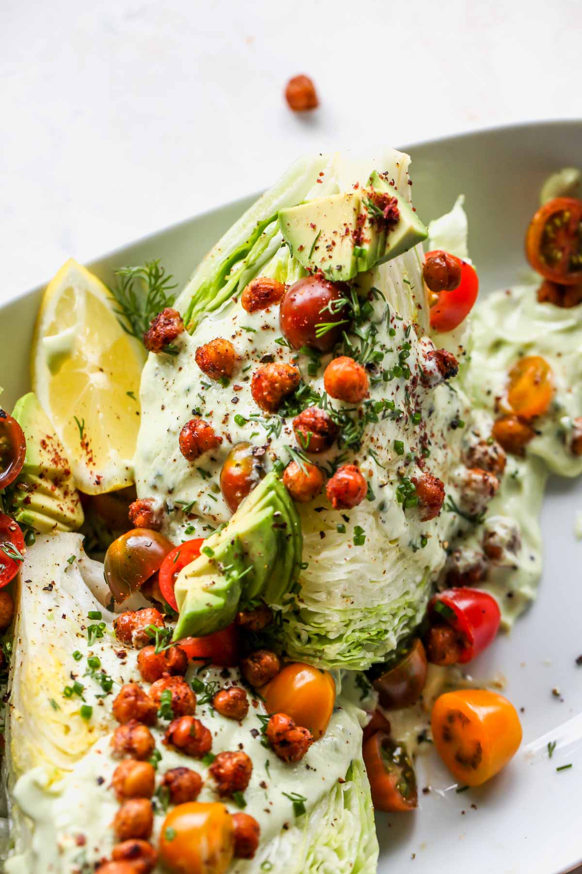 Wedge salads on a platter topped with crispy roasted chickpeas and ranch dressing