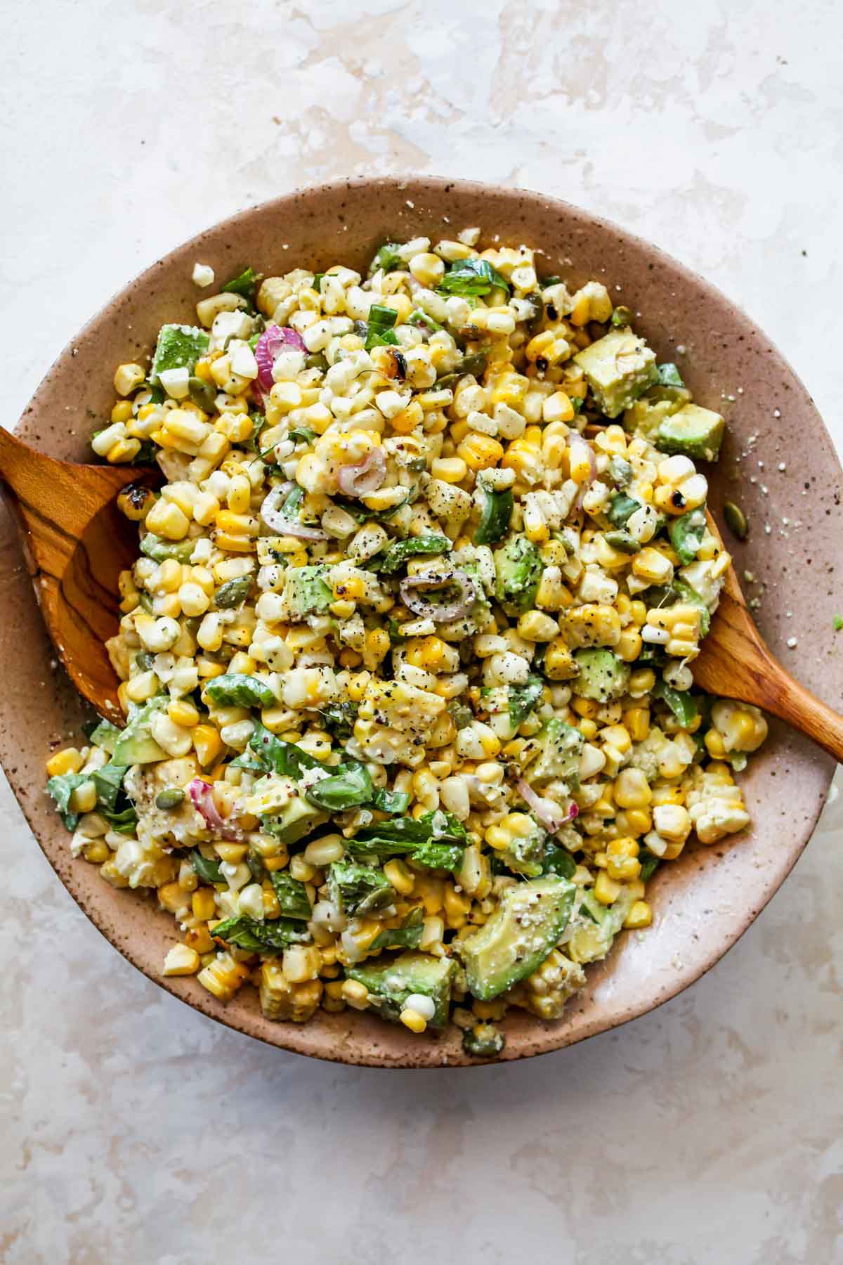 Salad ingredients being tossed together in a bowl