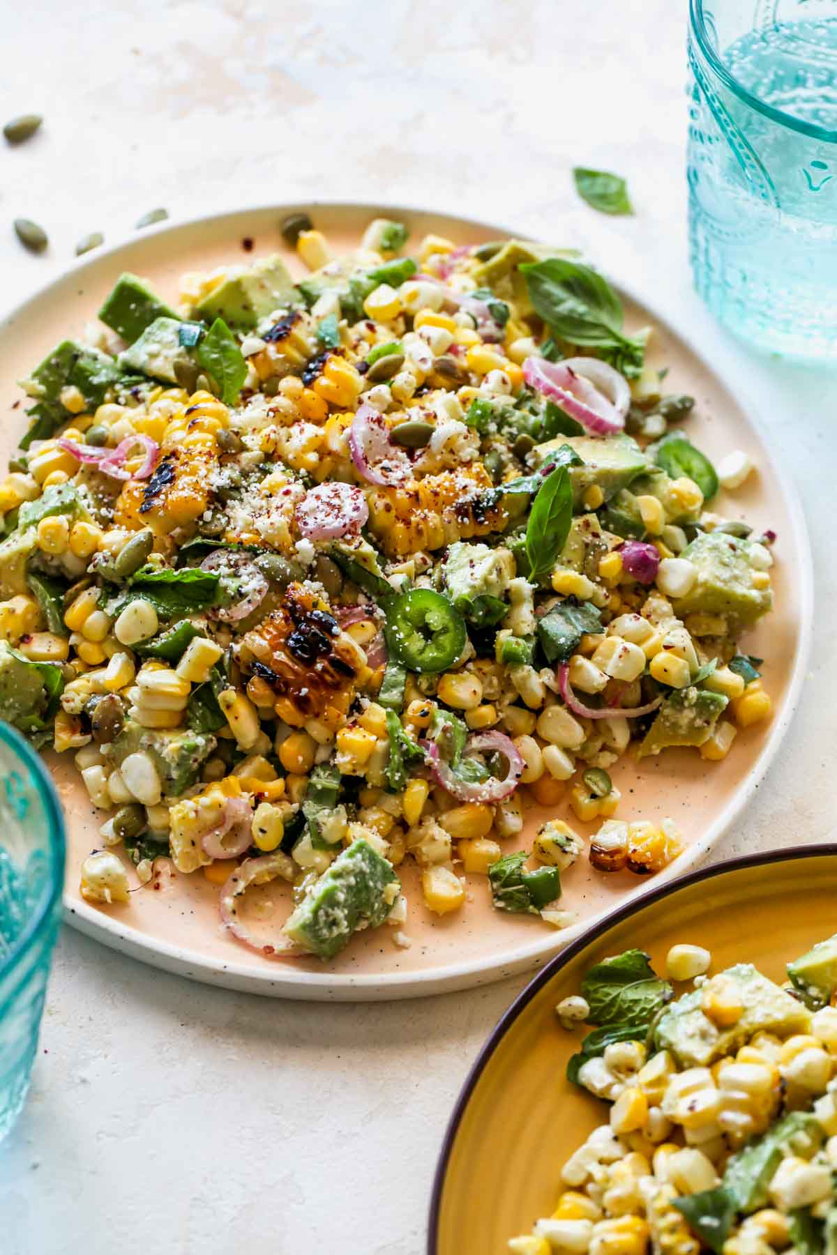 Avocado corn salad being served on a peach plate