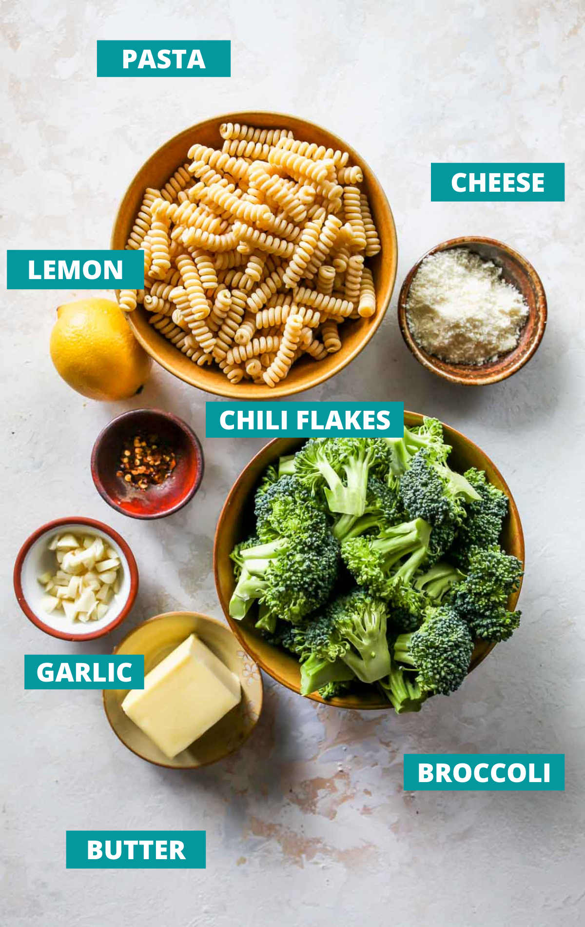 Broccoli pasta ingredients in separate bowls on a white board