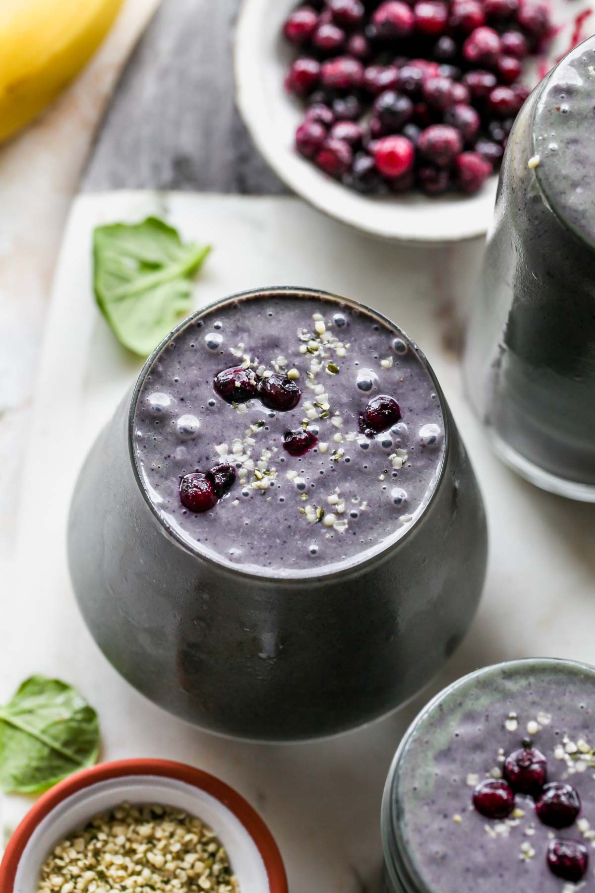 Blueberry smoothies on a white board topped with chia seeds and berries