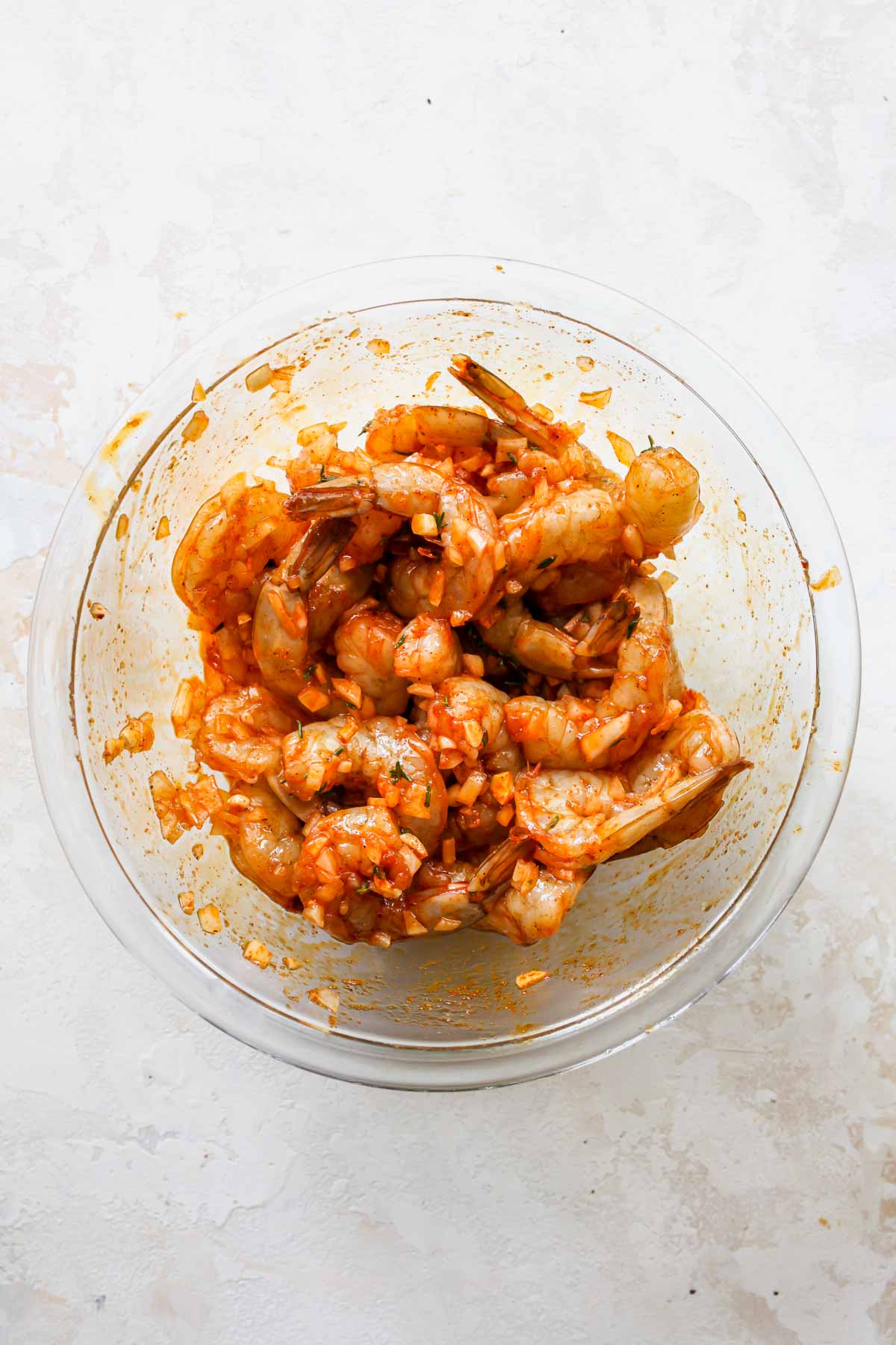 Shrimp marinating in spices, garlic, and thyme in a large bowl