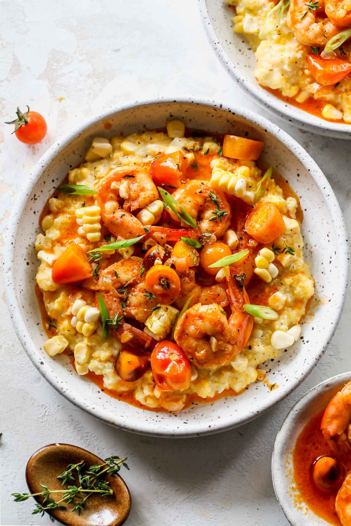 Cajun shrimp and grits in a white bowl topped with green onion