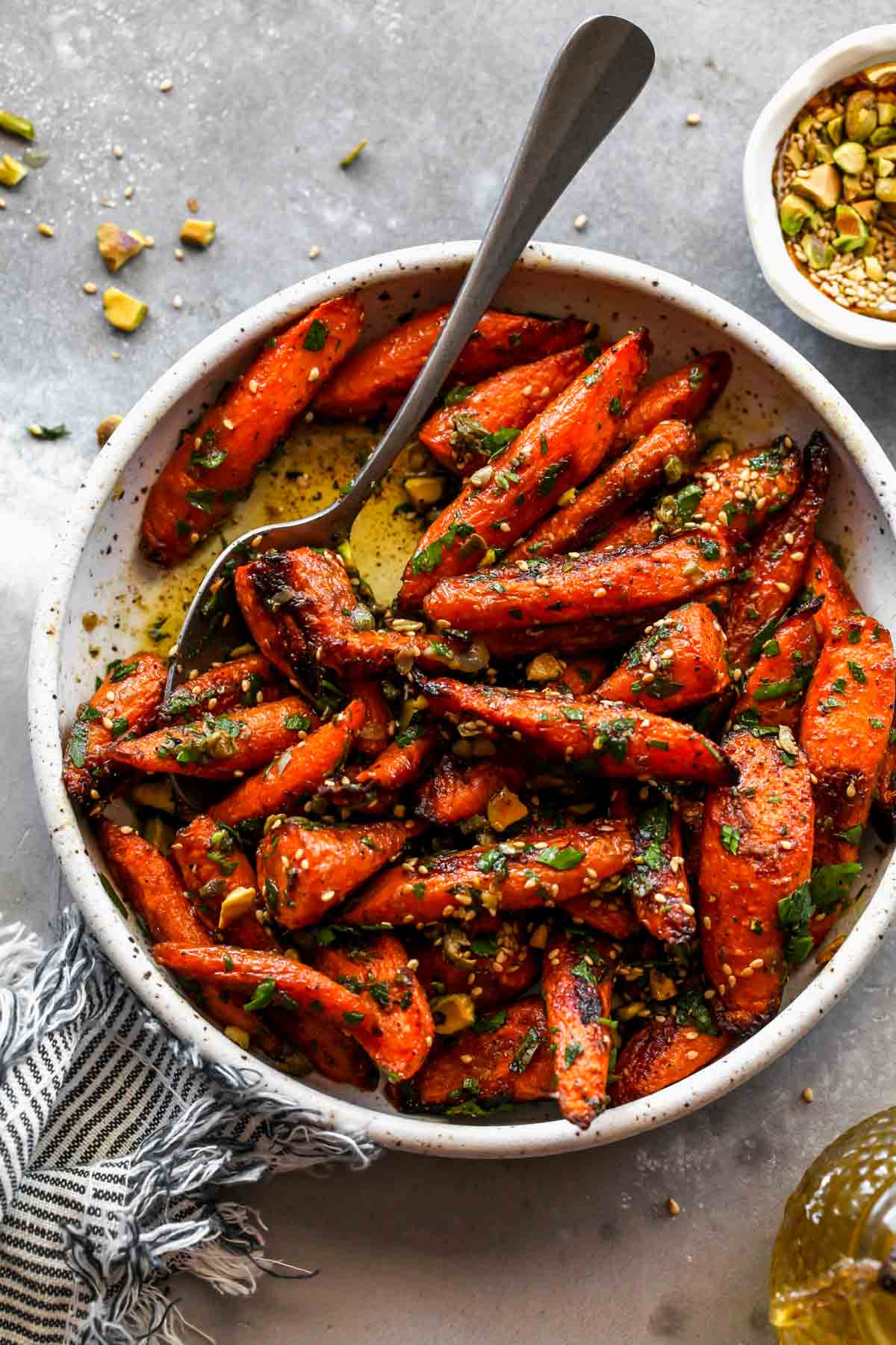 A spoon taking out a scoop of roasted carrots.