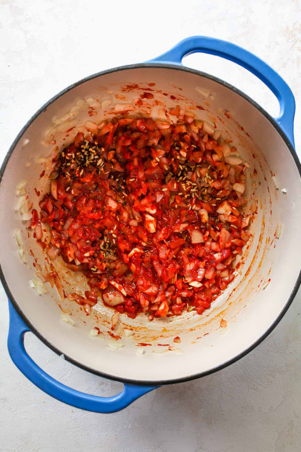 Onions, garlic, and tomato paste being simmered in a pot