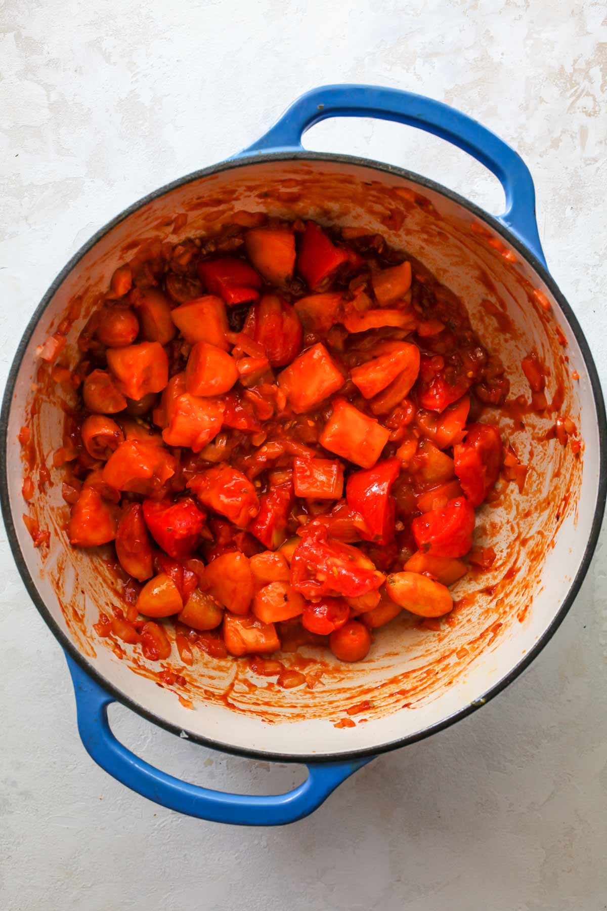 Fresh tomatoes being added to a pot of aromatics