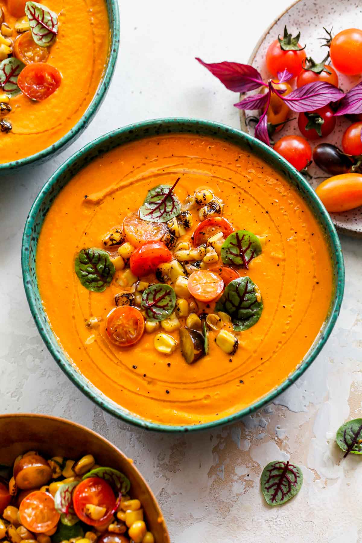 Tomato soup in a teal bowl topped with zesty corn salsa