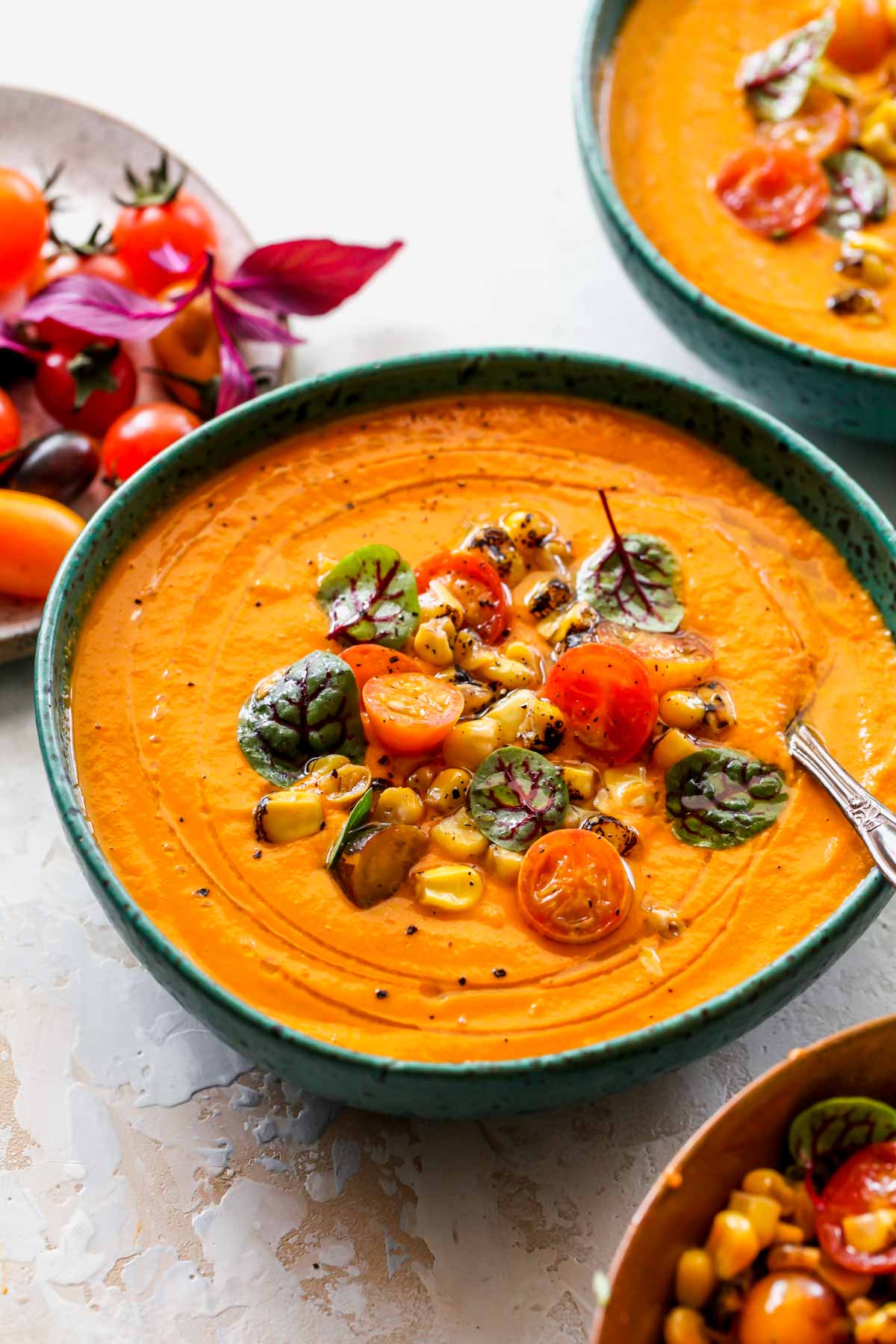 Serving of tomato basil soup in a blue bowl with a spoon resting on the side