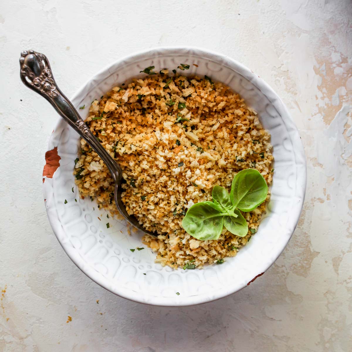 Toasted breadcrumbs and pine nuts in a bowl with fresh basil