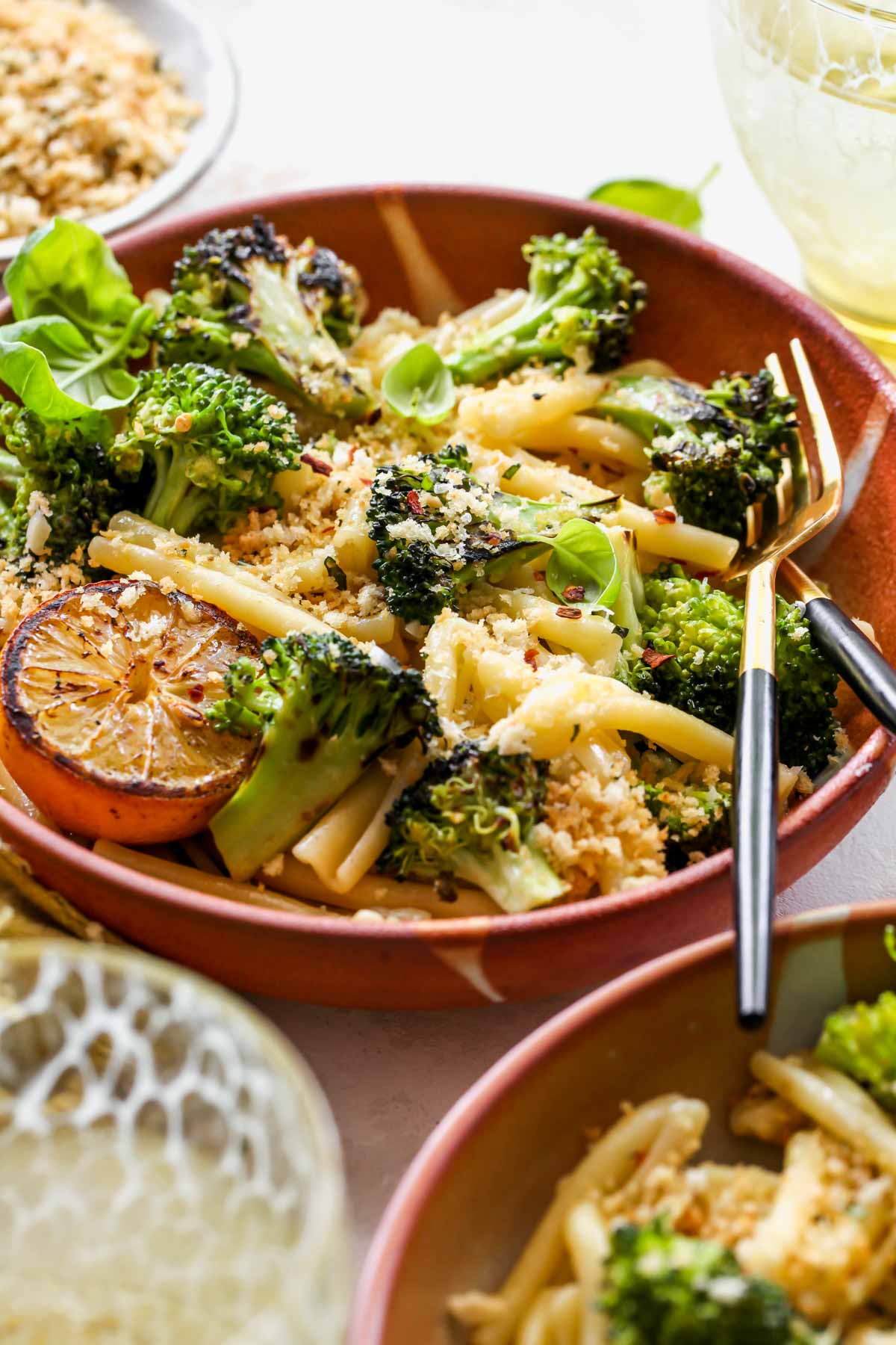 Lemon butter broccoli pasta styled in an orange bowl with a fork on the side
