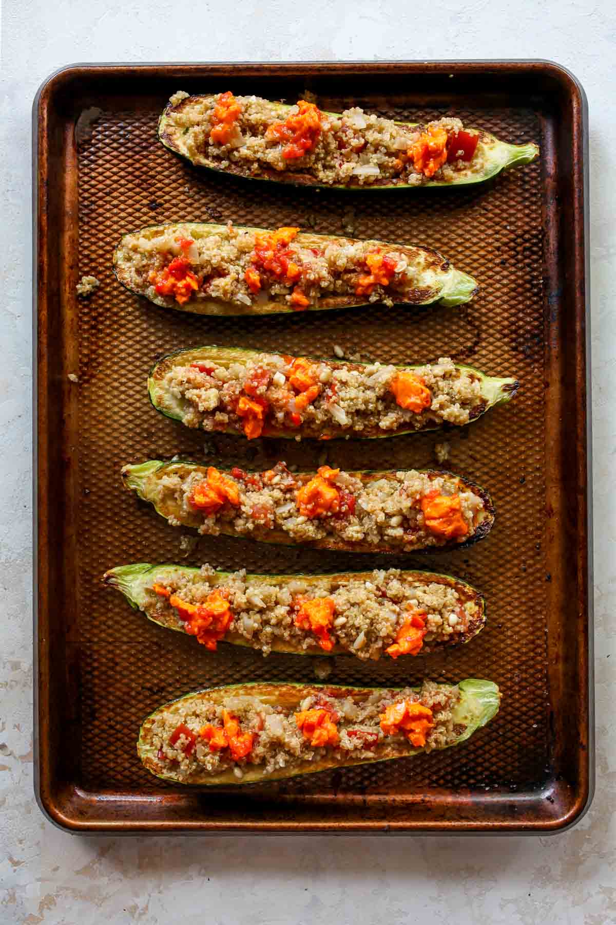 Zucchini boats being stuffed with quinoa mixture before baking
