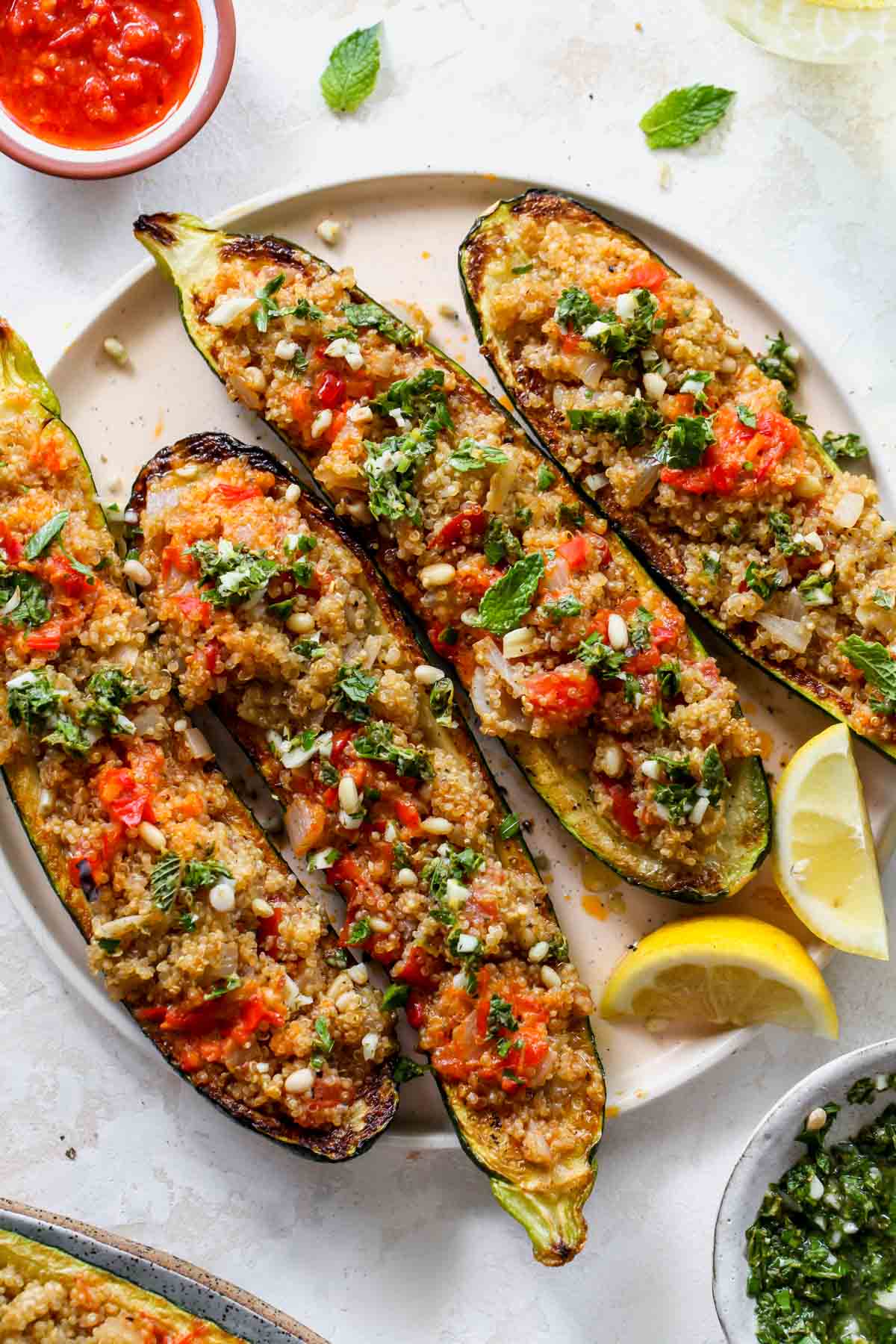 Zucchini boats filled with quinoa on a plate with lemon wedges