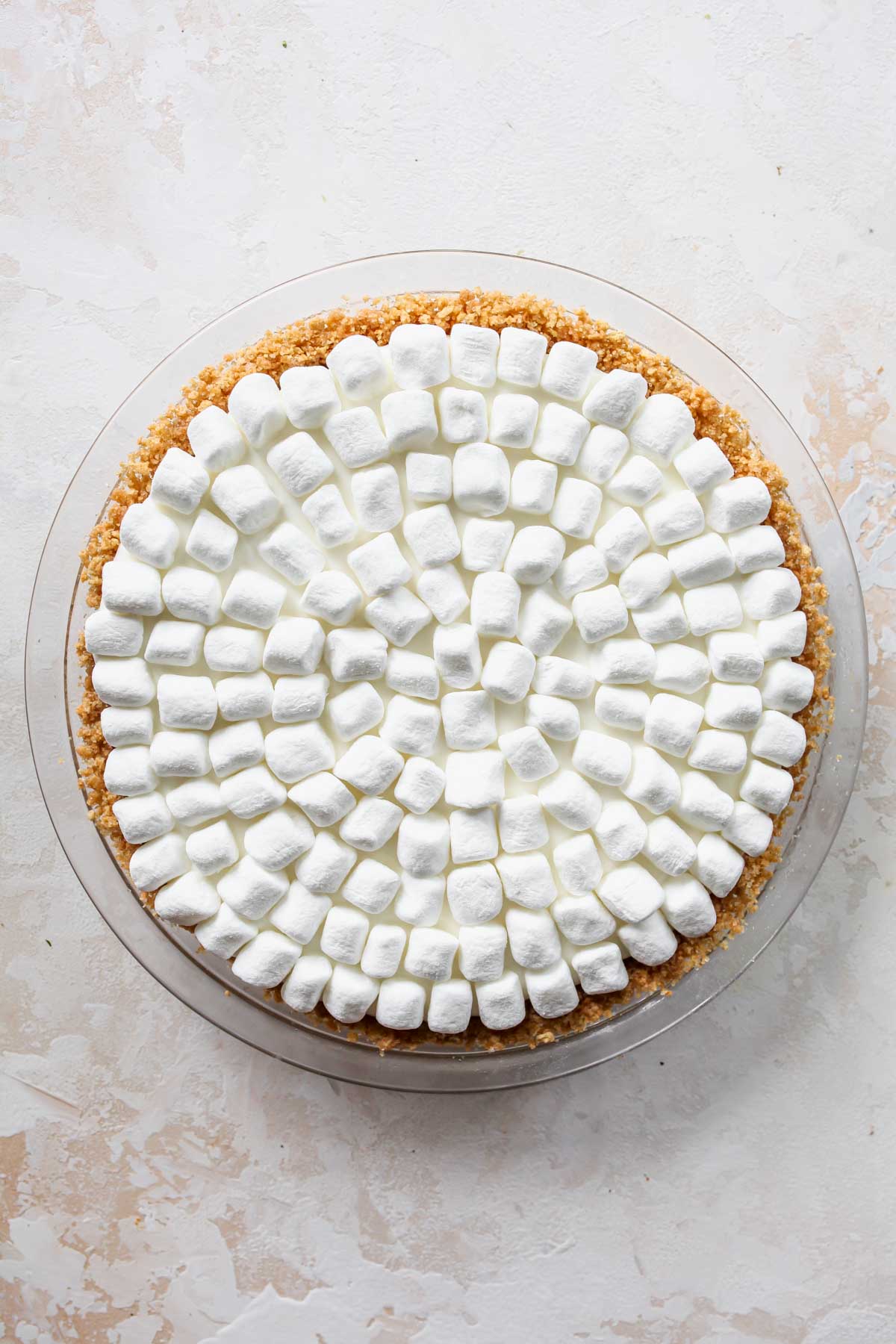 Mini marshmallows being placed on top of a pie