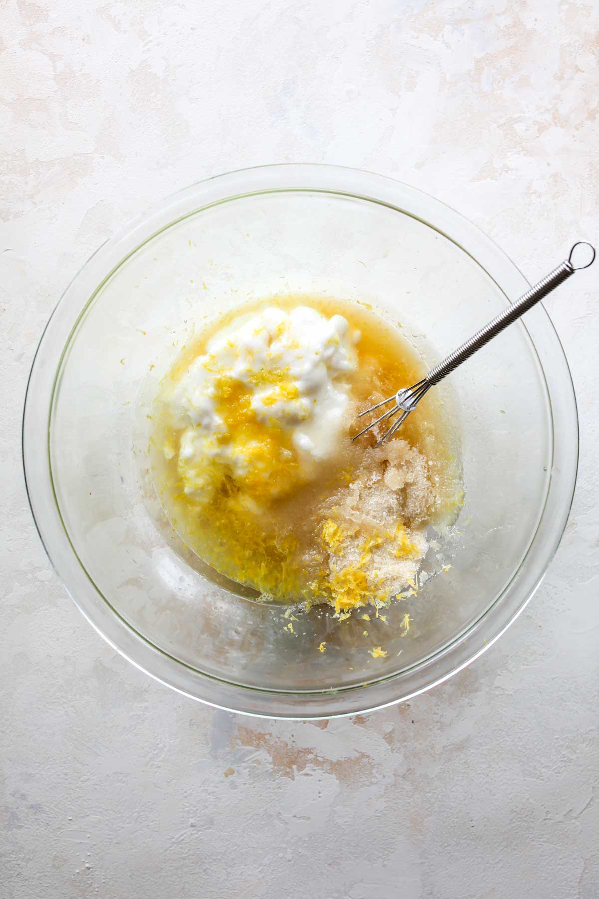 Yogurt, lemon juice, sugar, and vanilla being whisked in a bowl