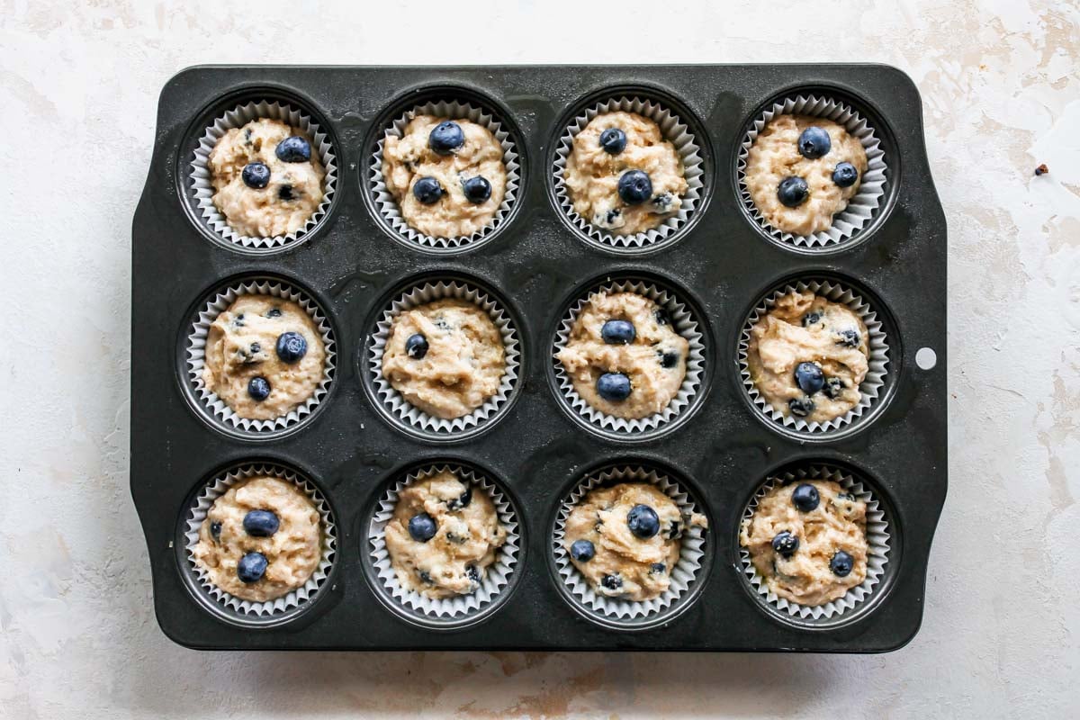 A muffin tray being filled with muffin batter