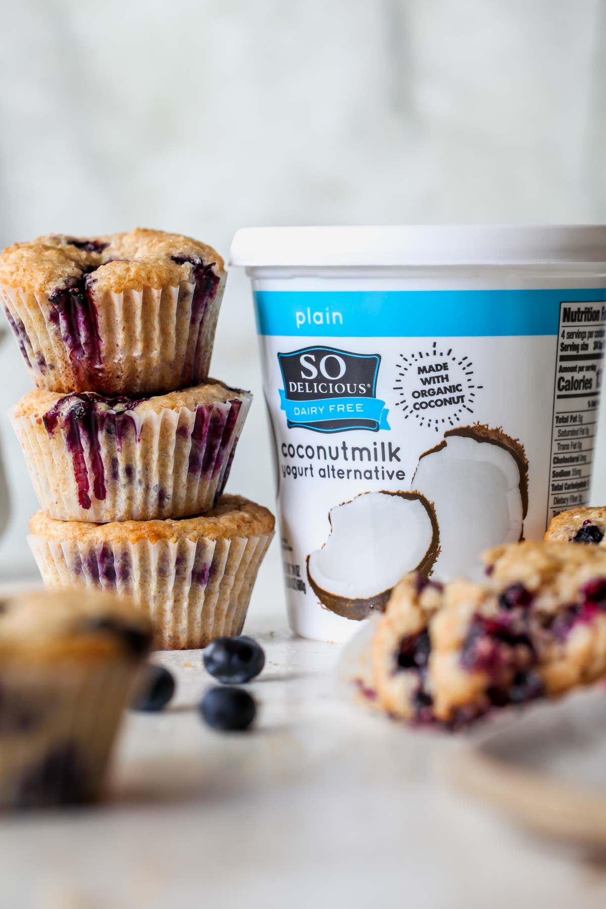 Blueberry muffins stacked against a container of So Delicious Yogurt
