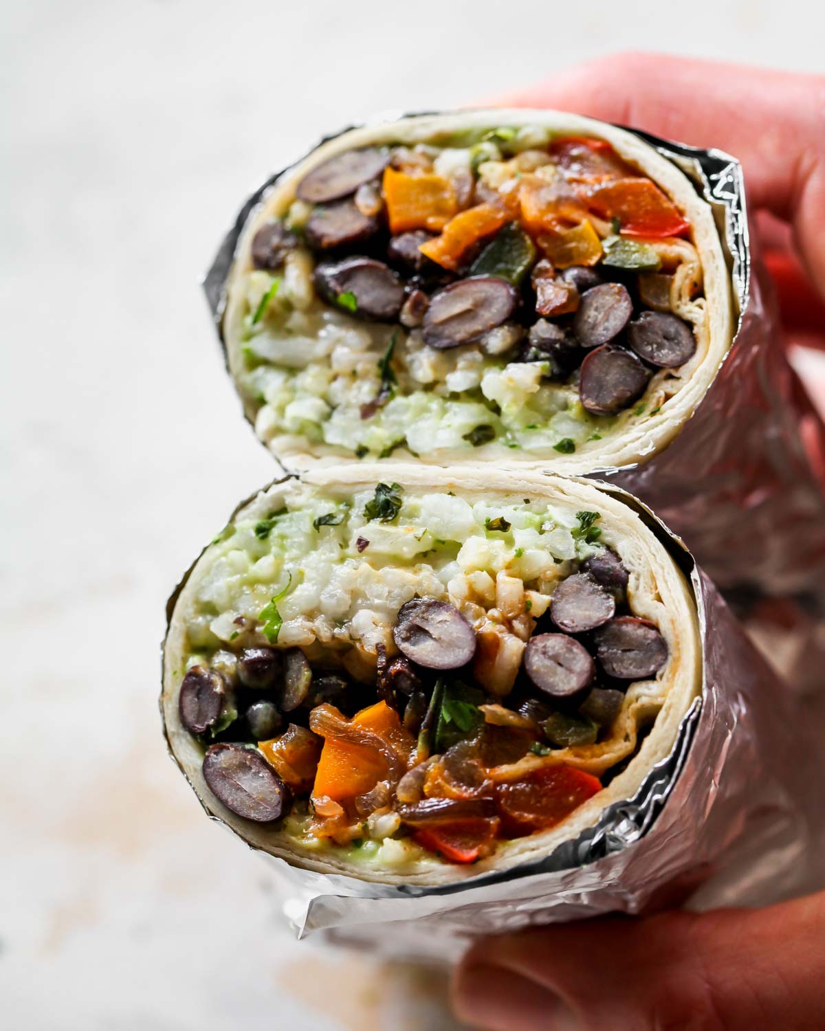 Vegetarian burrito wrapped in foil and sliced in half