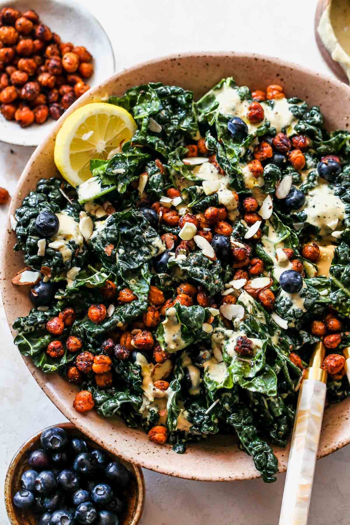 Vegan Kale Caesar salad styled in a pink bowl with blueberries and chickpeas