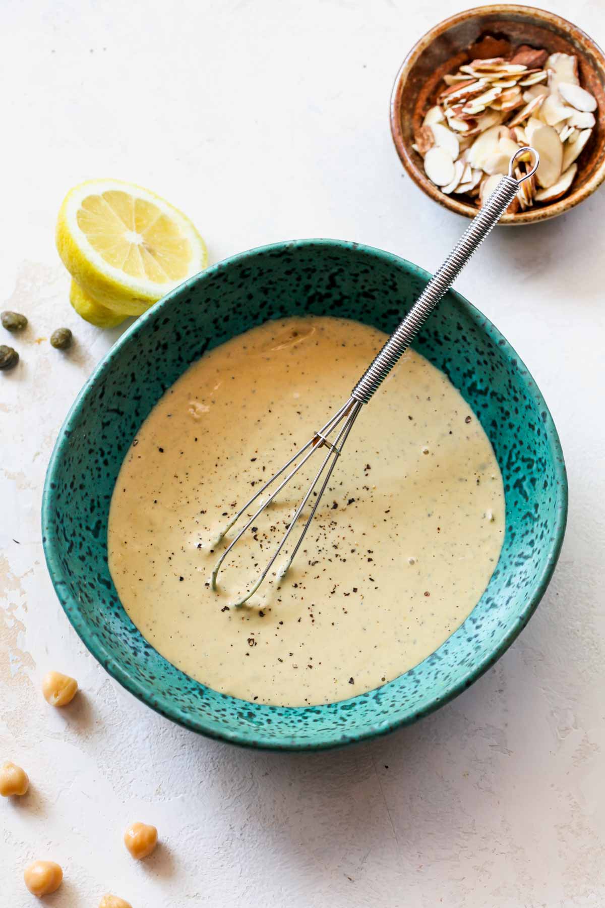 Vegan Tahini Caesar dressing being whisked in a teal bowl