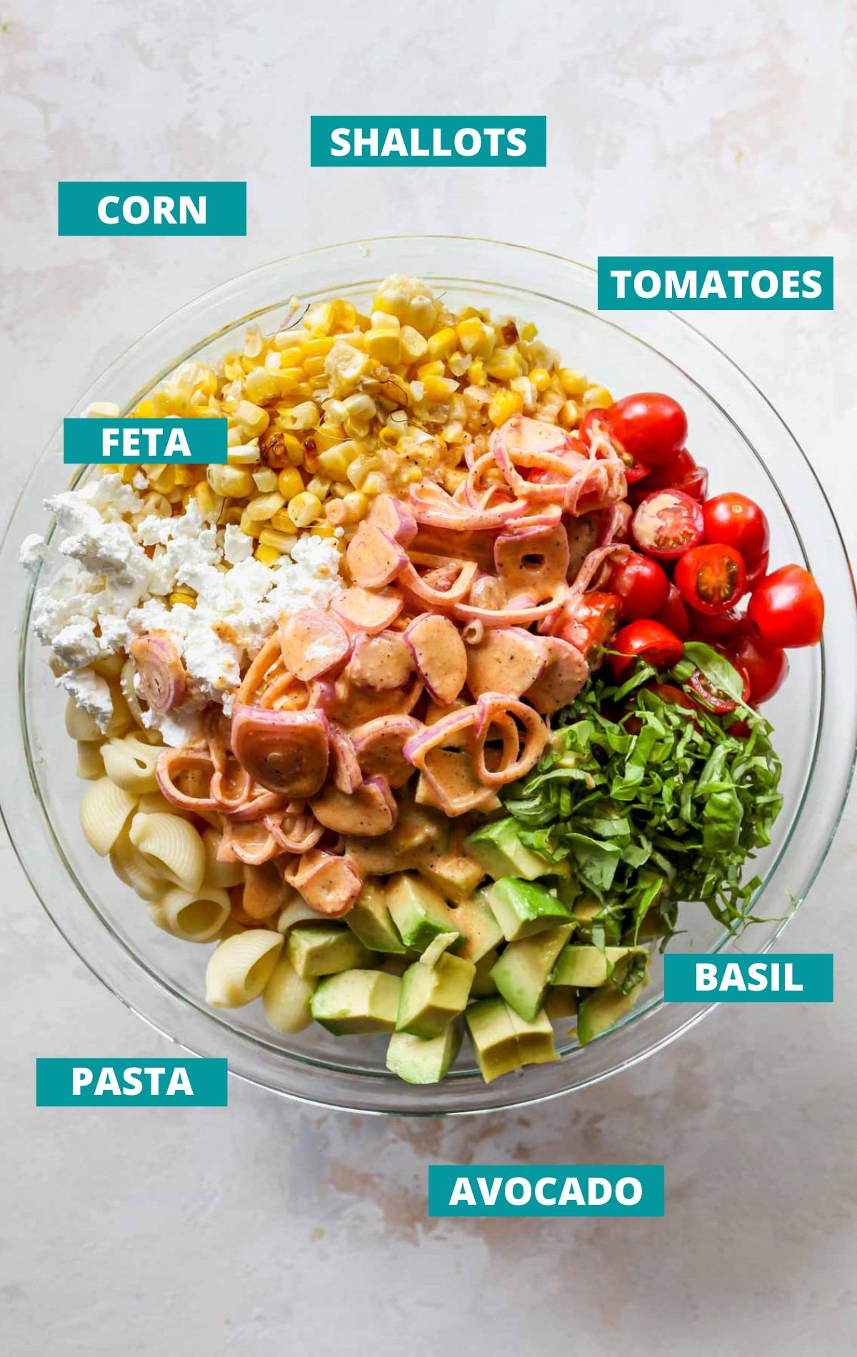 Pasta salad ingredients in a bowl with blue labels