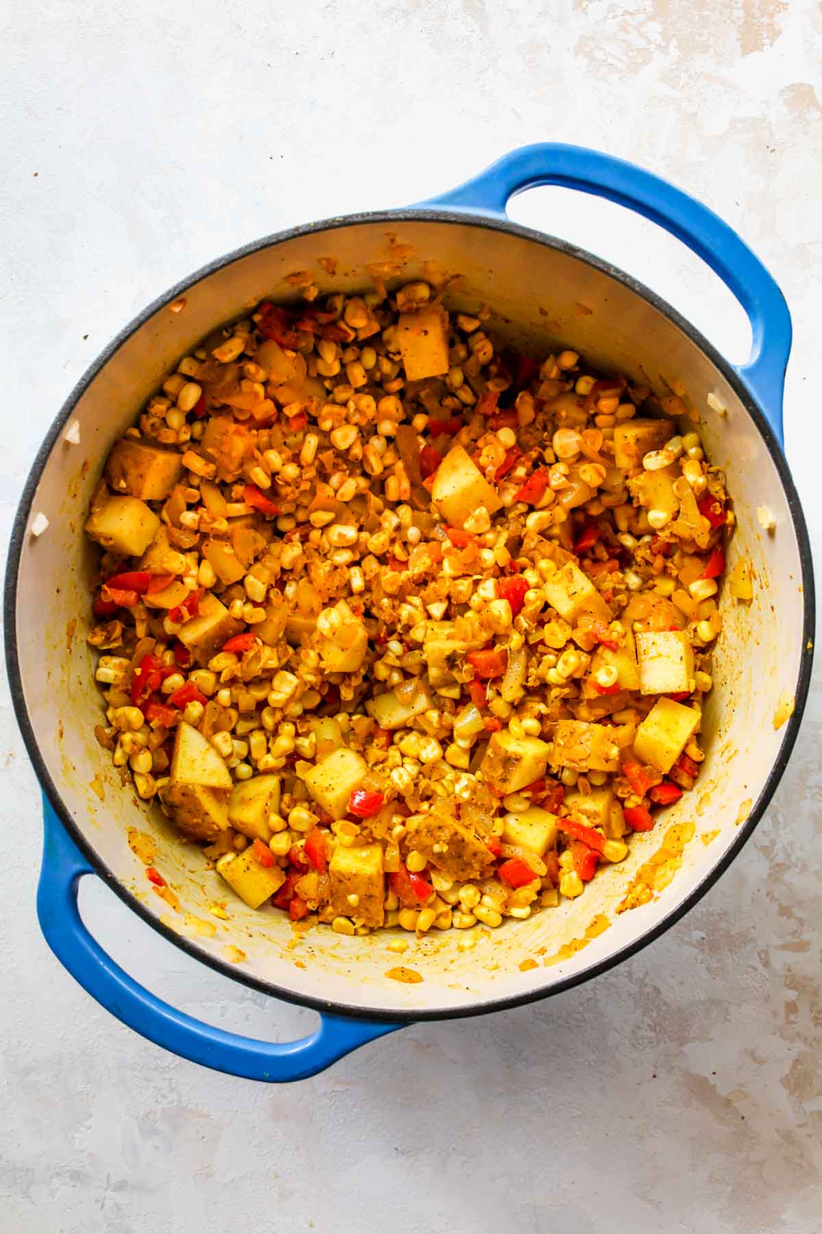 Diced potatoes and corn kernels being added to a pot