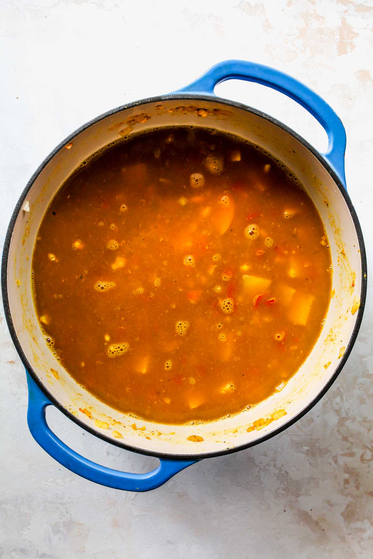 Vegetable broth being added to a pot of soup