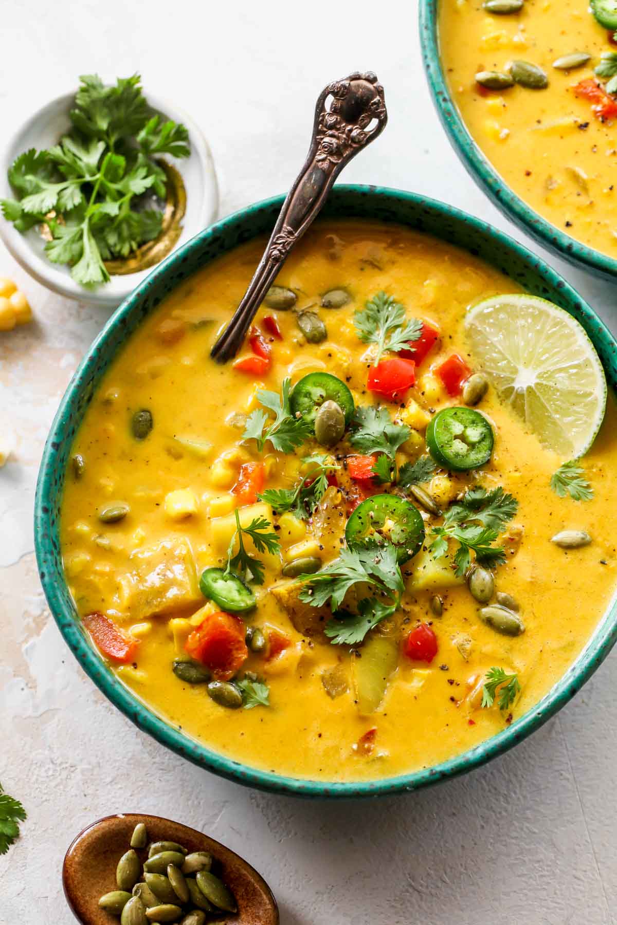 A spoon resting in a bowl of coconut corn chowder
