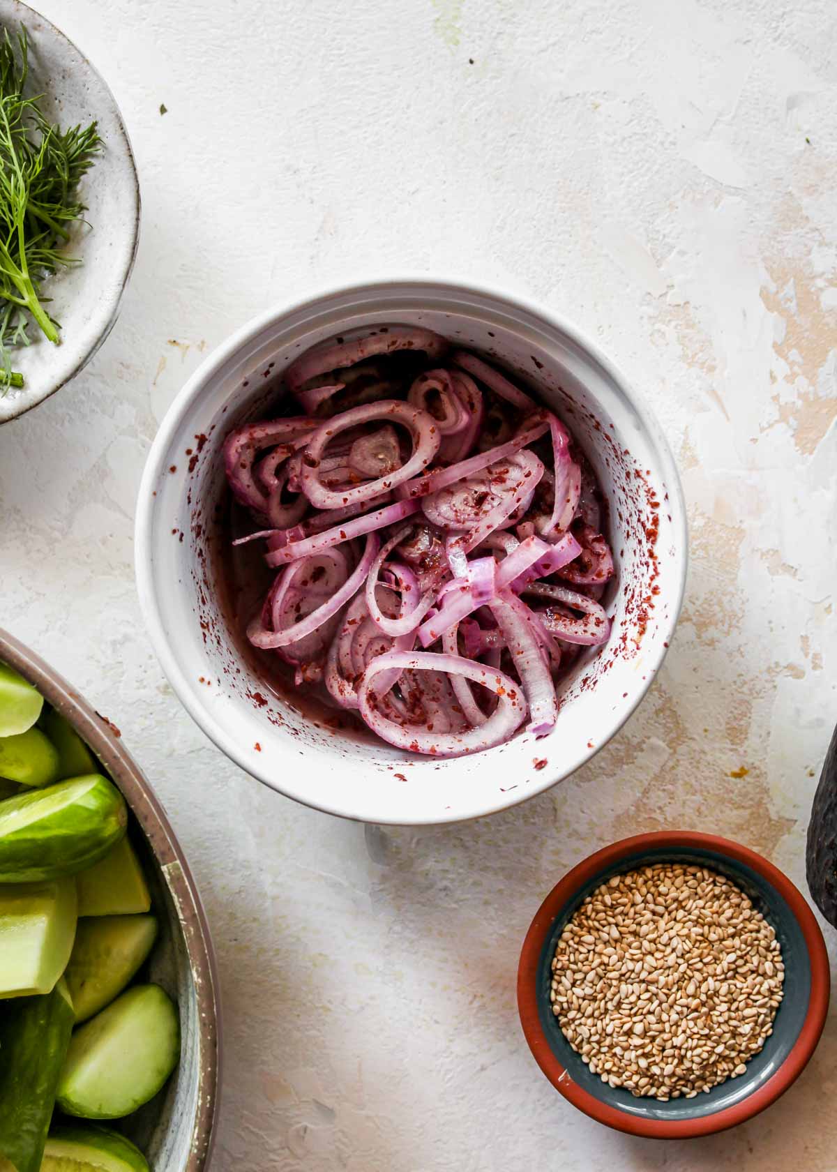 Shallots marinating in rice vinegar and sumac in a small bowl