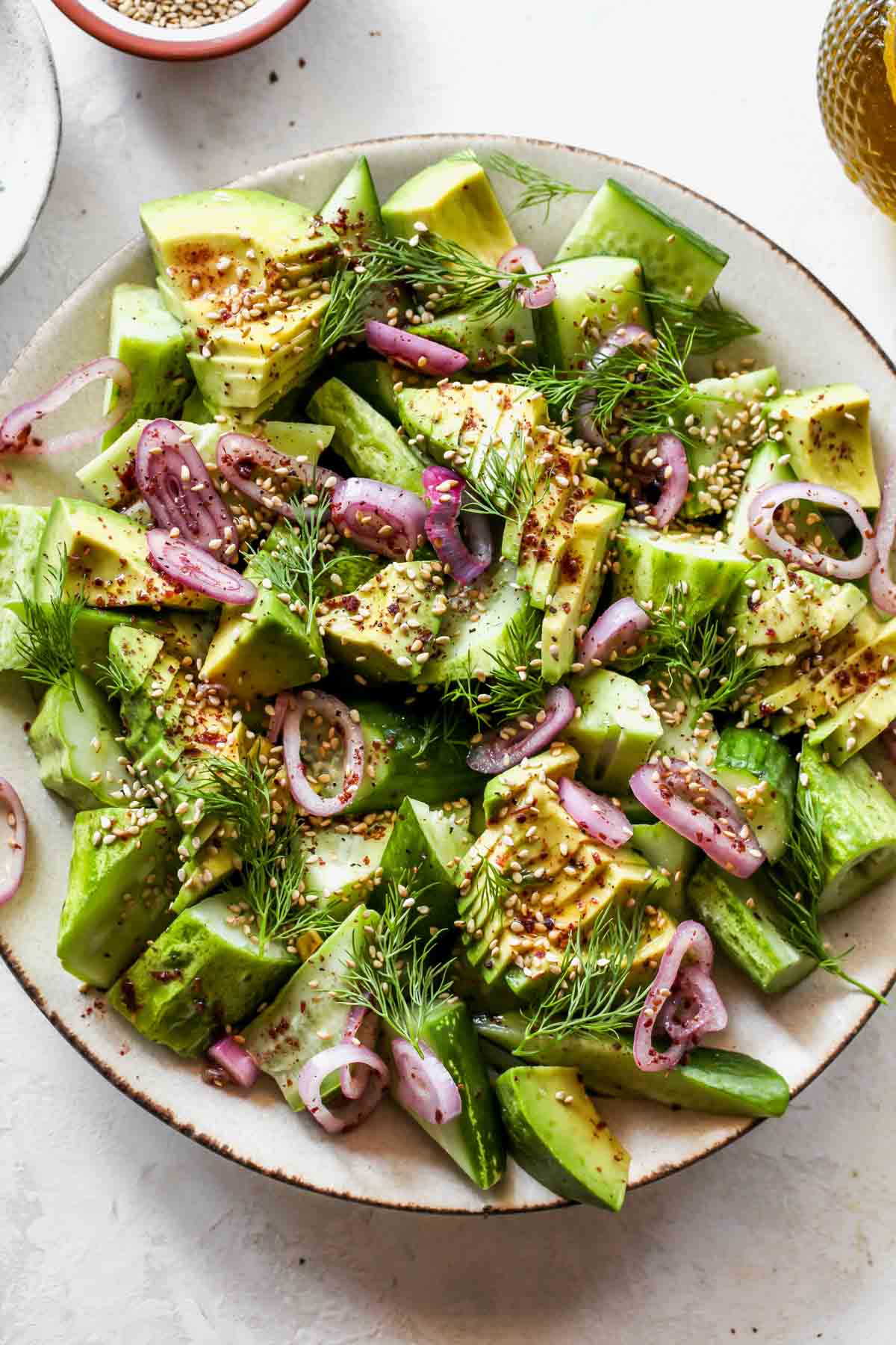 Cucumber avocado salad styled on a tan plate