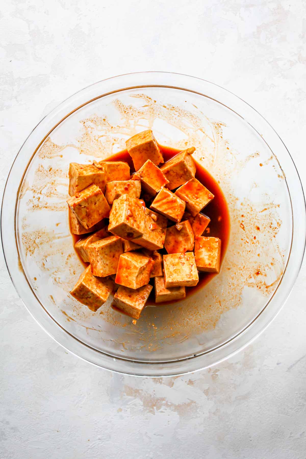 Cubes of tofu marinating in a large mixing bowl