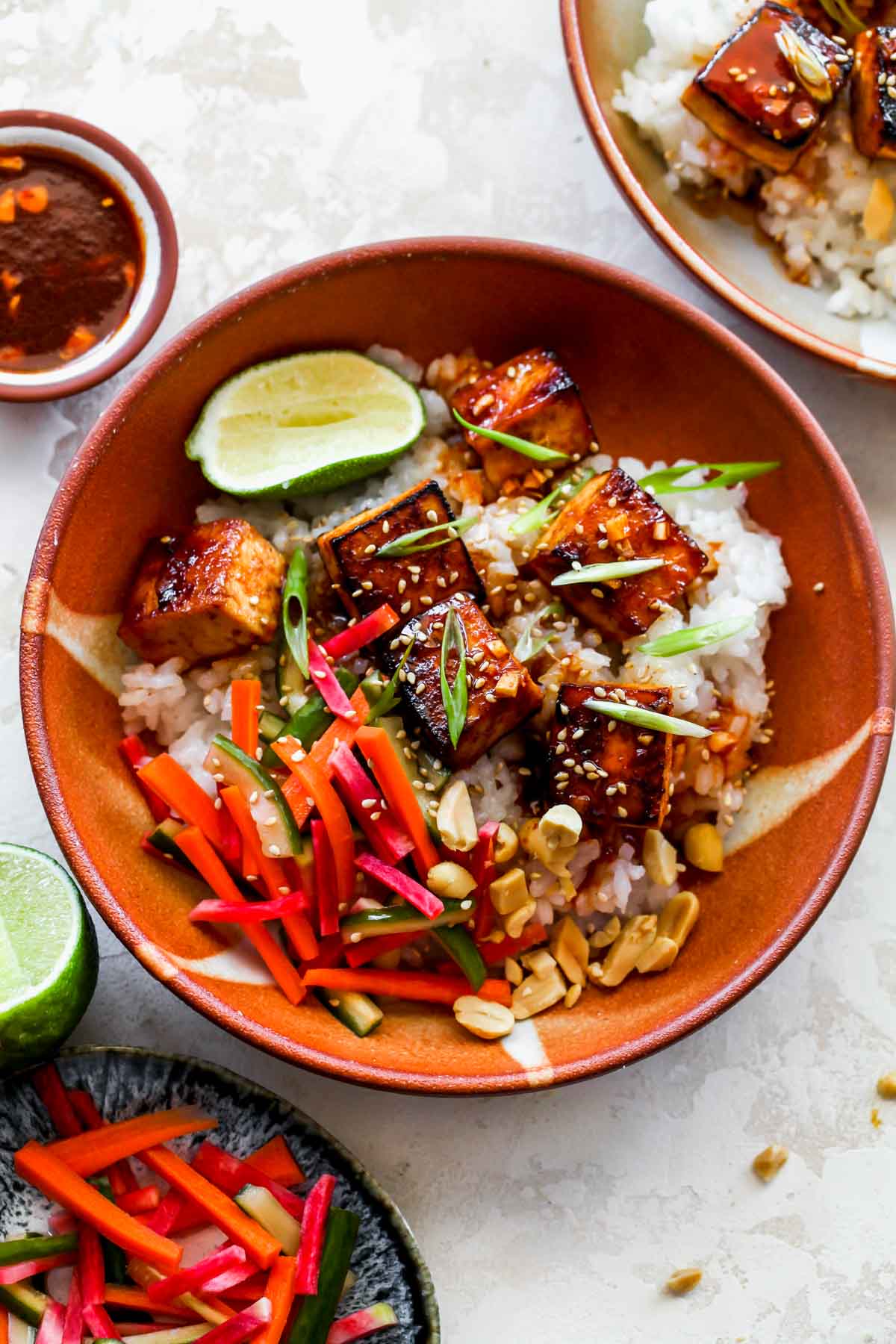 Gochujang marinated tofu and rice in a bowl topped with pickled veggies