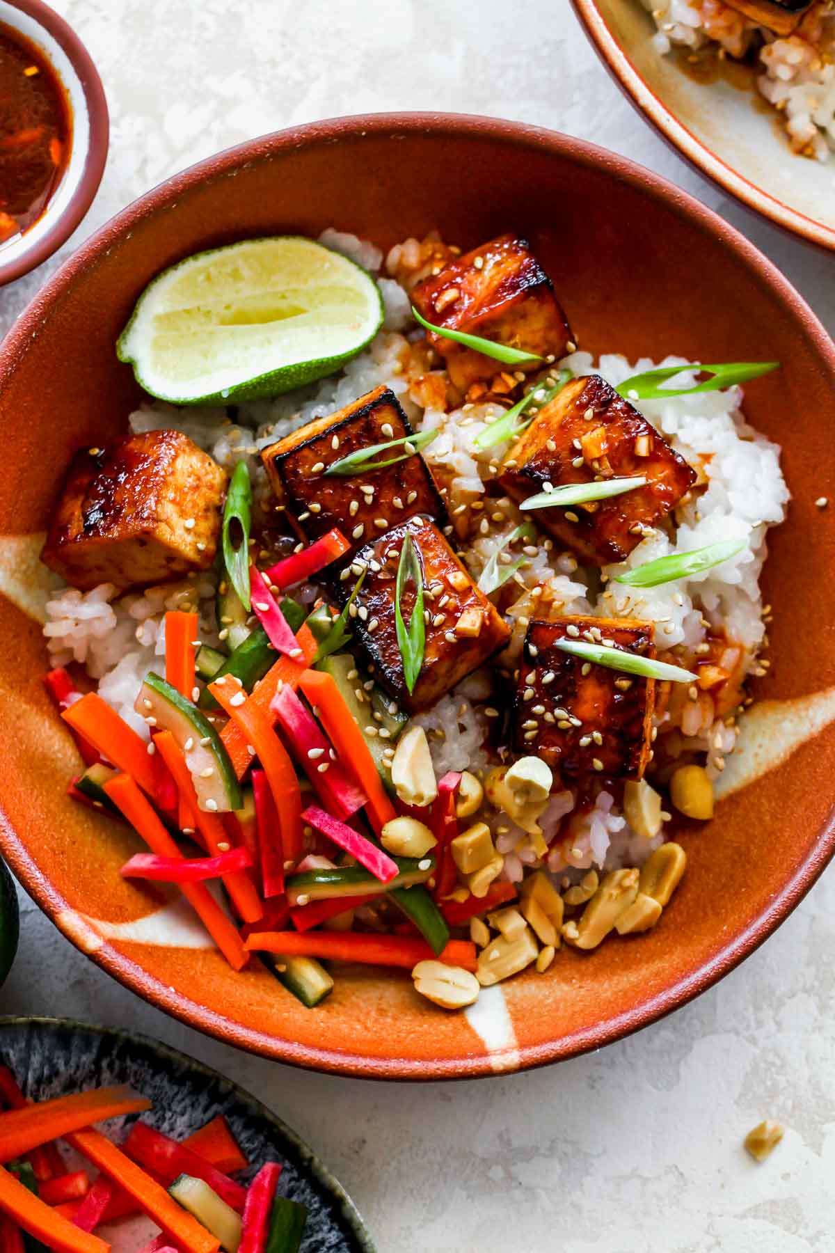 Tofu, rice, and pickled vegetables in an orange bowl