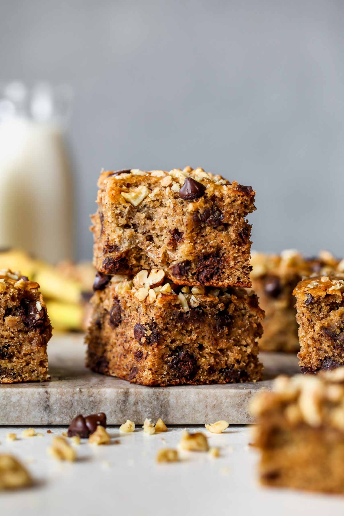 Two banana bread bars stacked on top of one another on a cutting board
