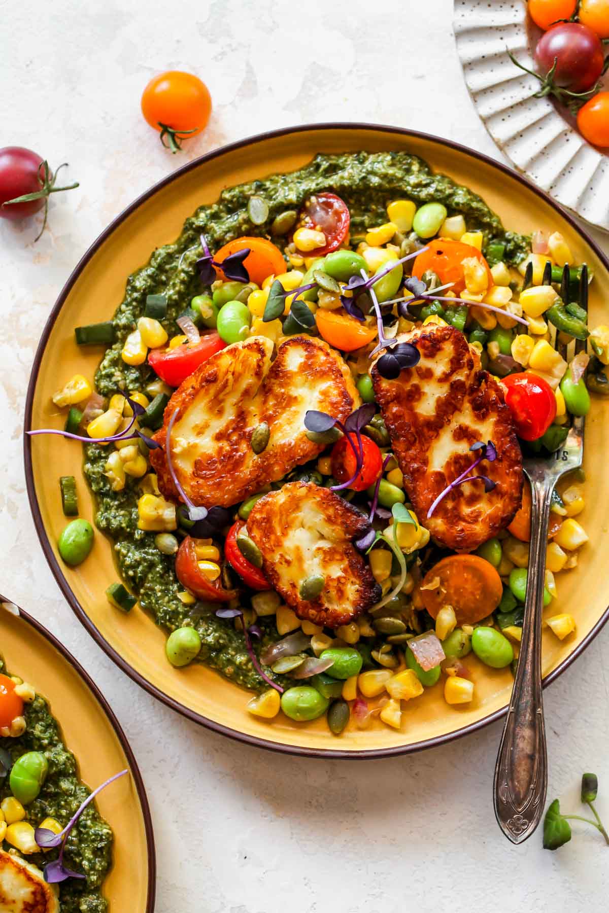Corn succotash over basil pesto topped with chunks of halloumi cheese